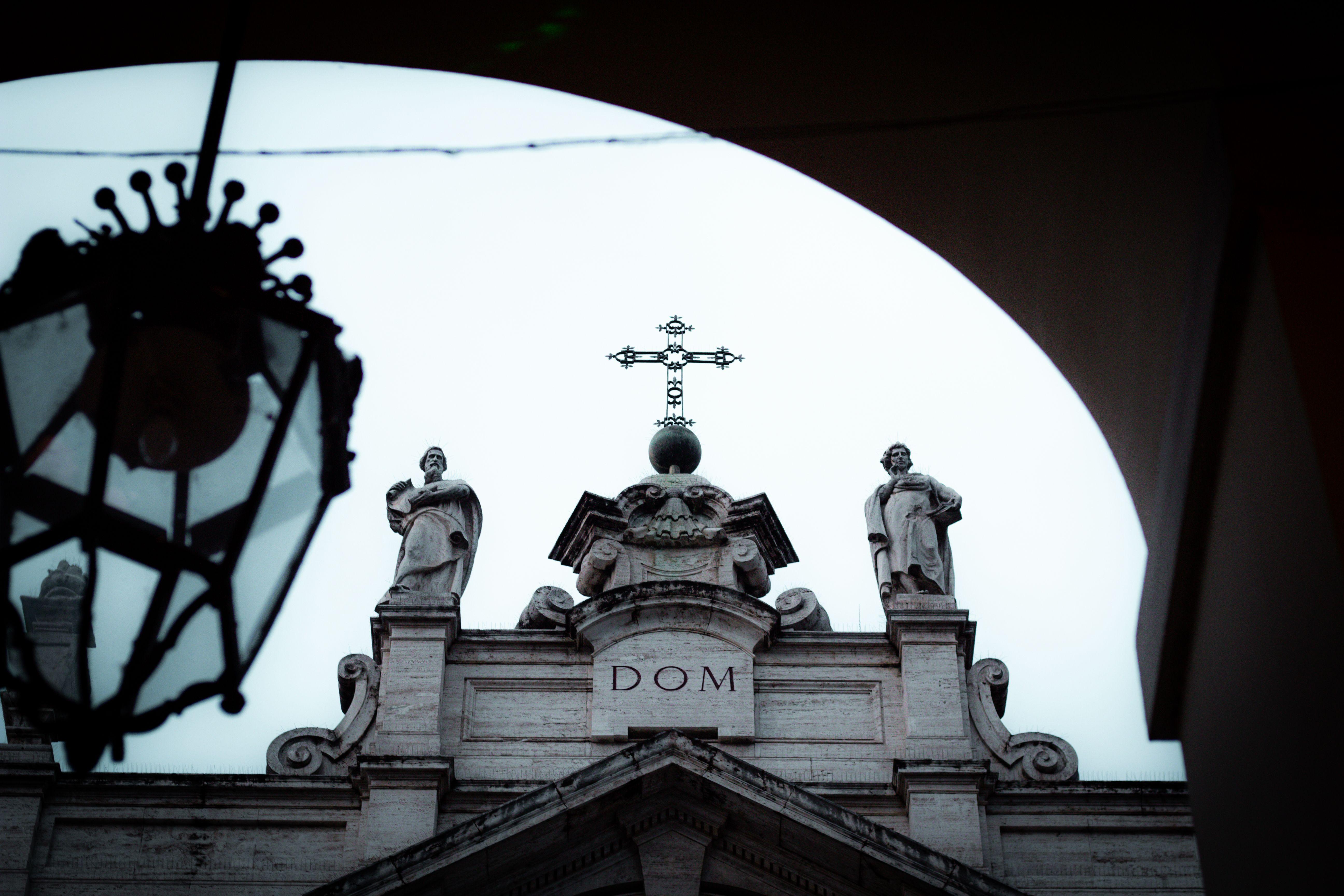 Close-up of a historic church facade in Turin, featuring statues and a cross against the sky.