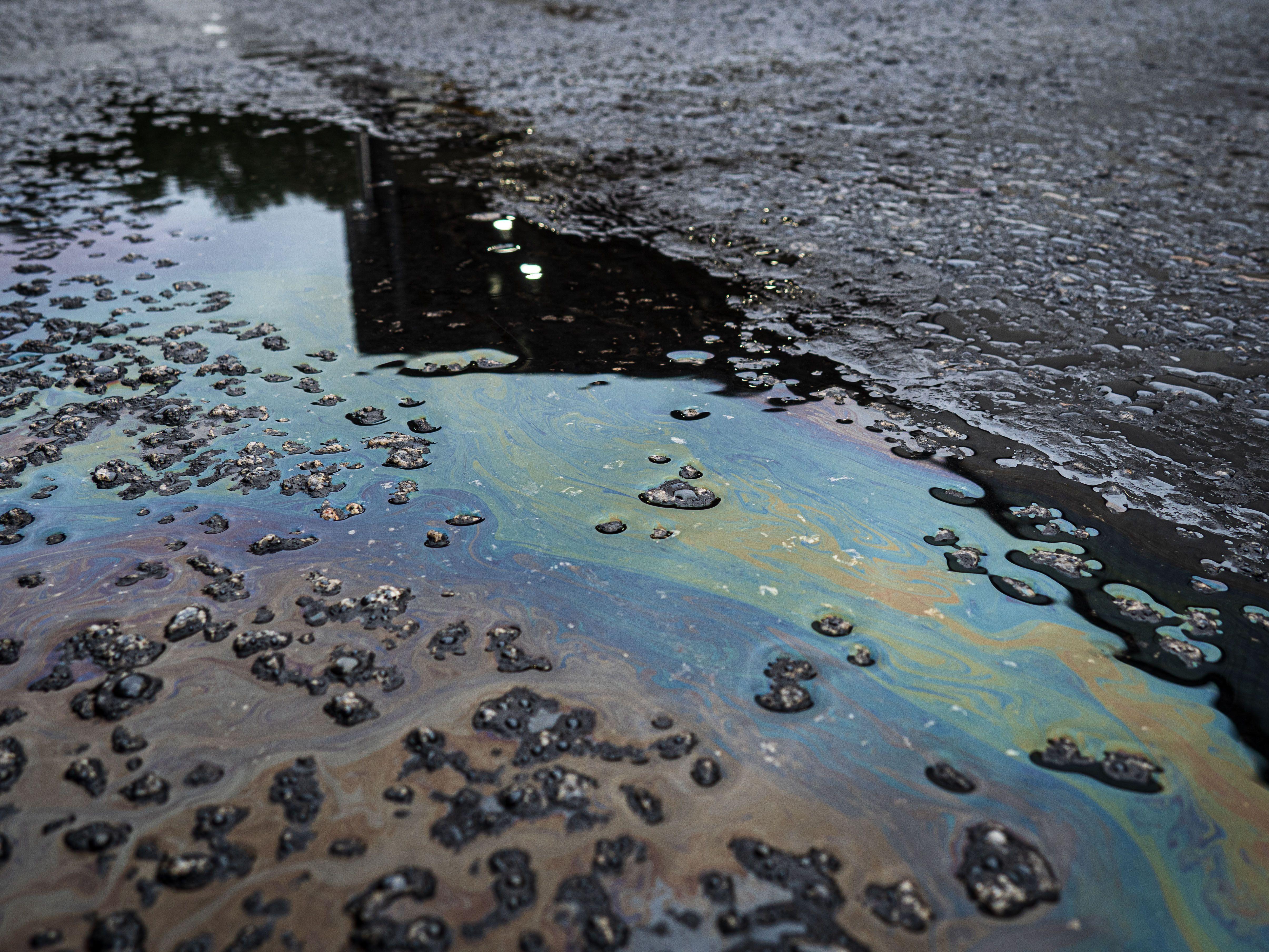 A vivid iridescent oil spill on rough asphalt surface, highlighting environmental contamination.