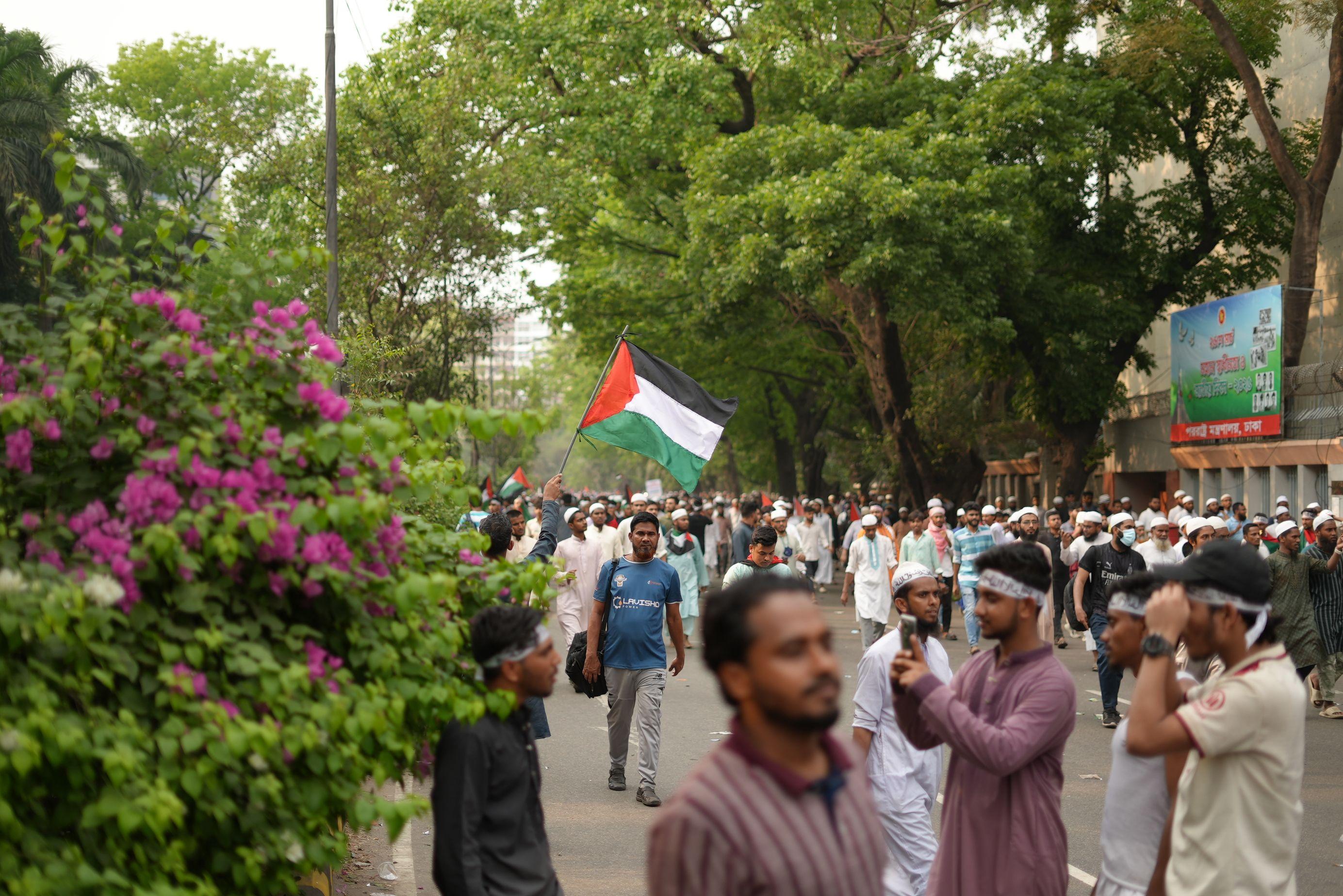 A crowd participates in a pro-Palestine rally in Dhaka, Bangladesh, waving flags in solidarity.