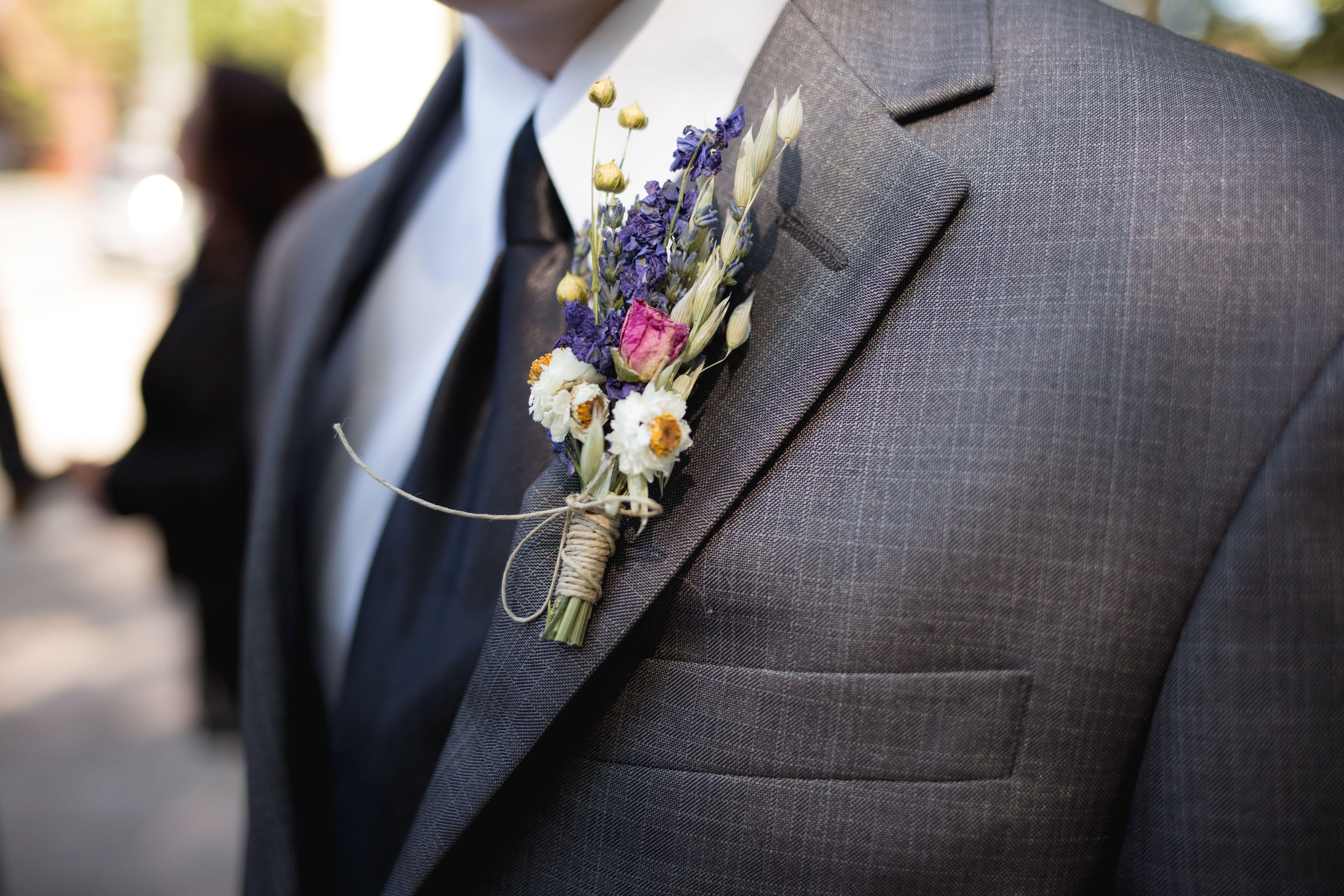 Close-up of an elegant groom wearing a designer suit and floral boutonniere during a wedding ceremony.
