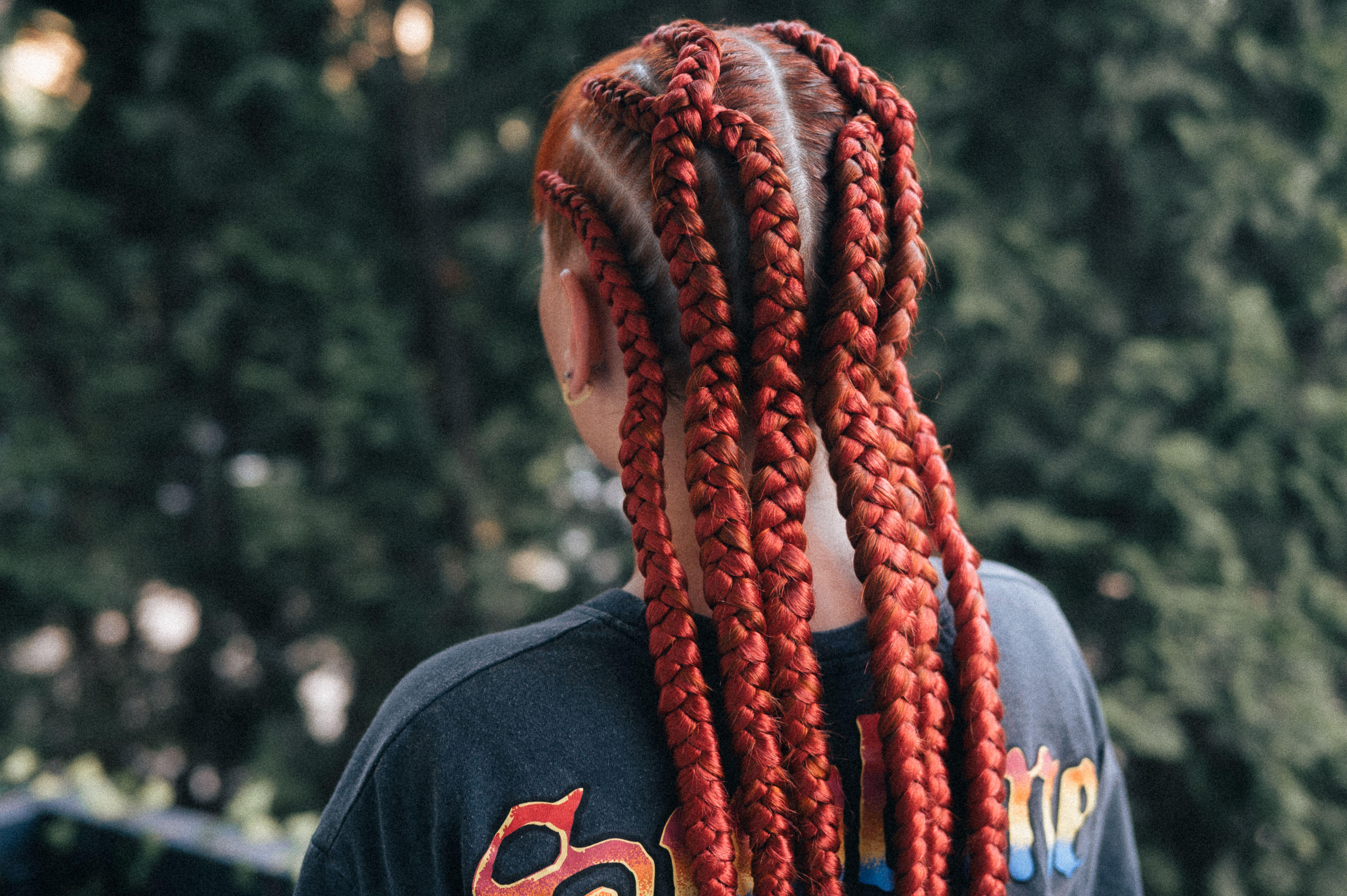 Close-up of vibrant red braids on an adult outdoors.