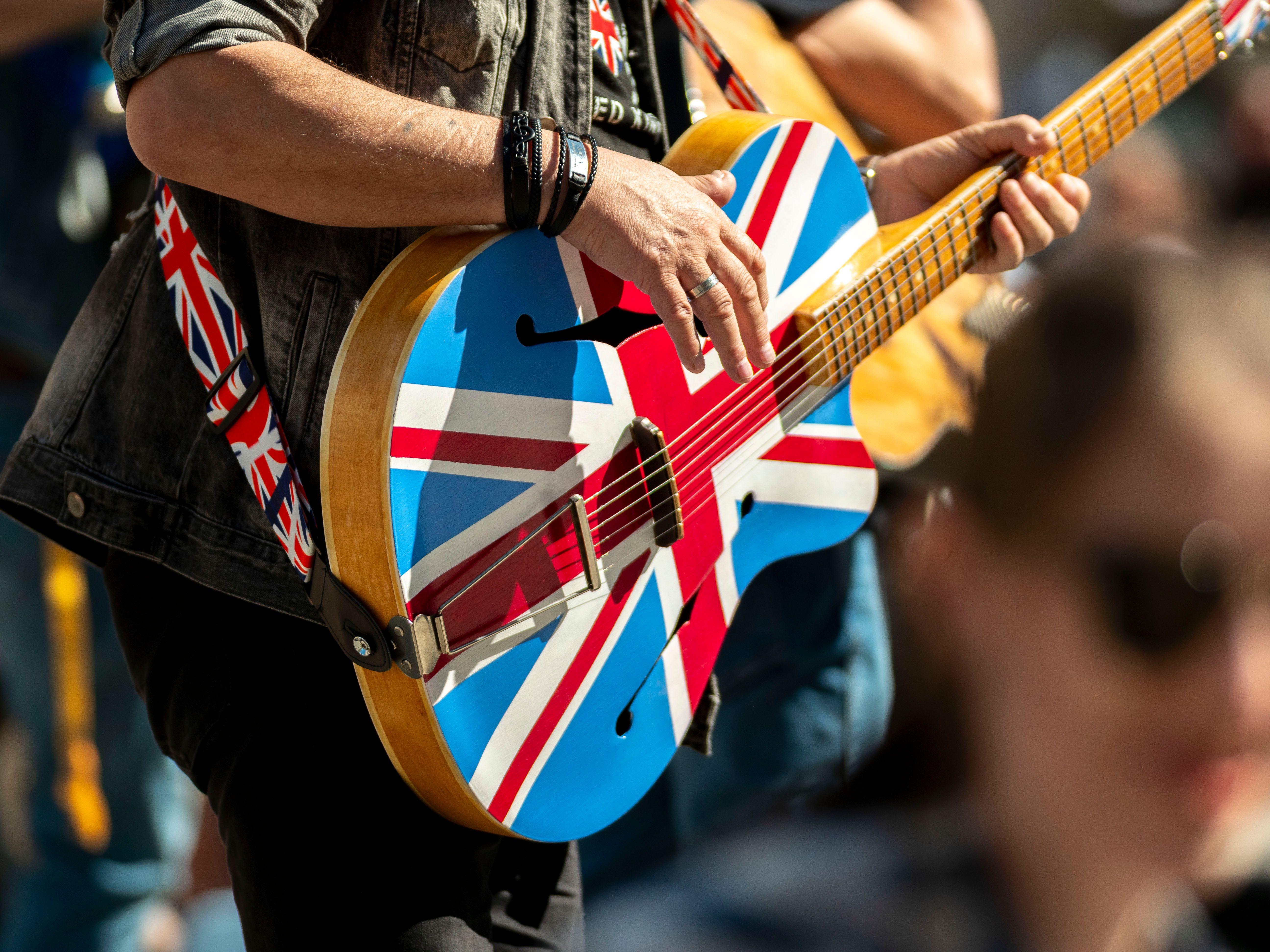 Close-up of a musician playing a Union Jack guitar at an outdoor event in Wrocław, Poland.