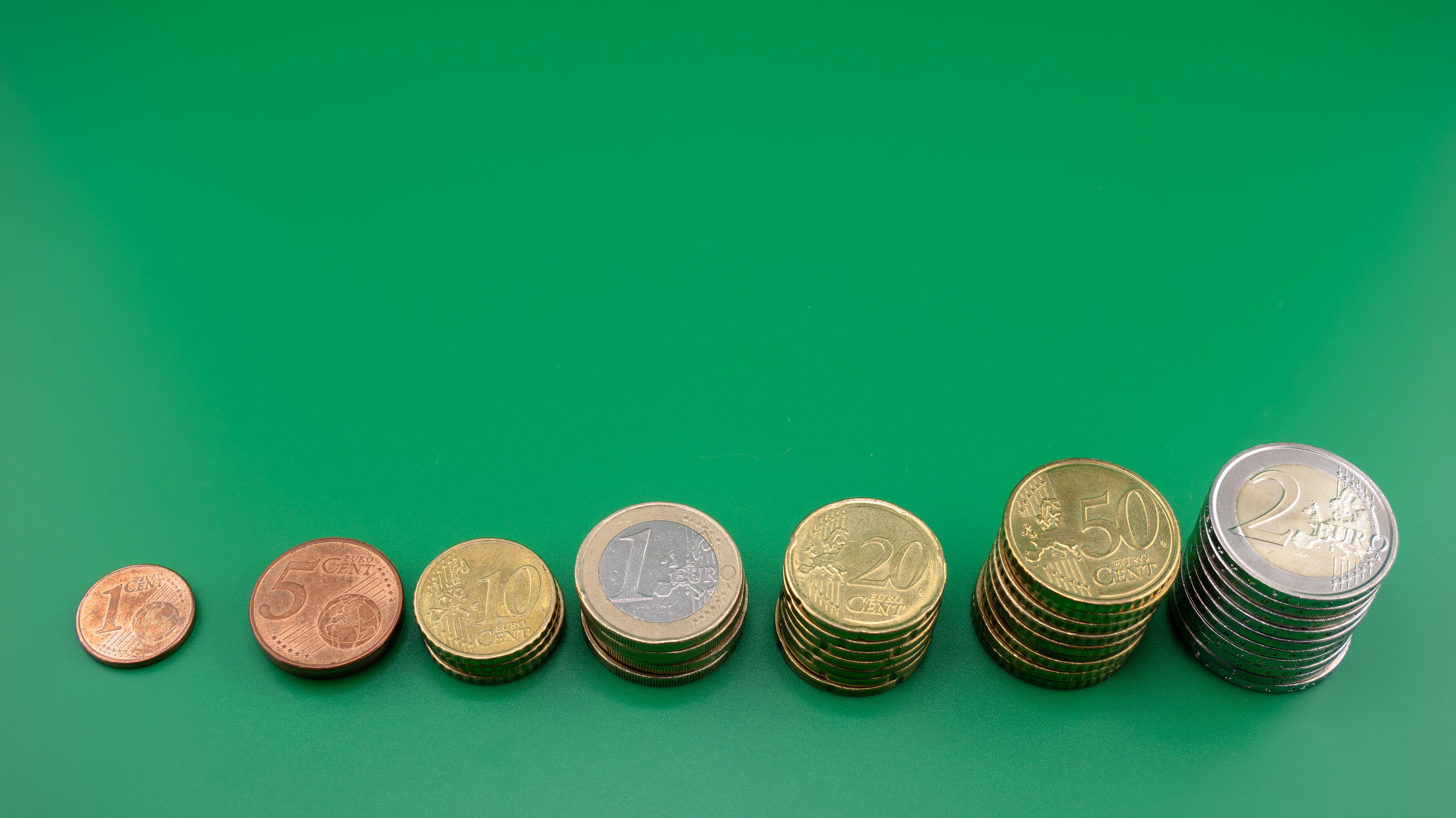 Various euro coins stacked incrementally on a vibrant green background.