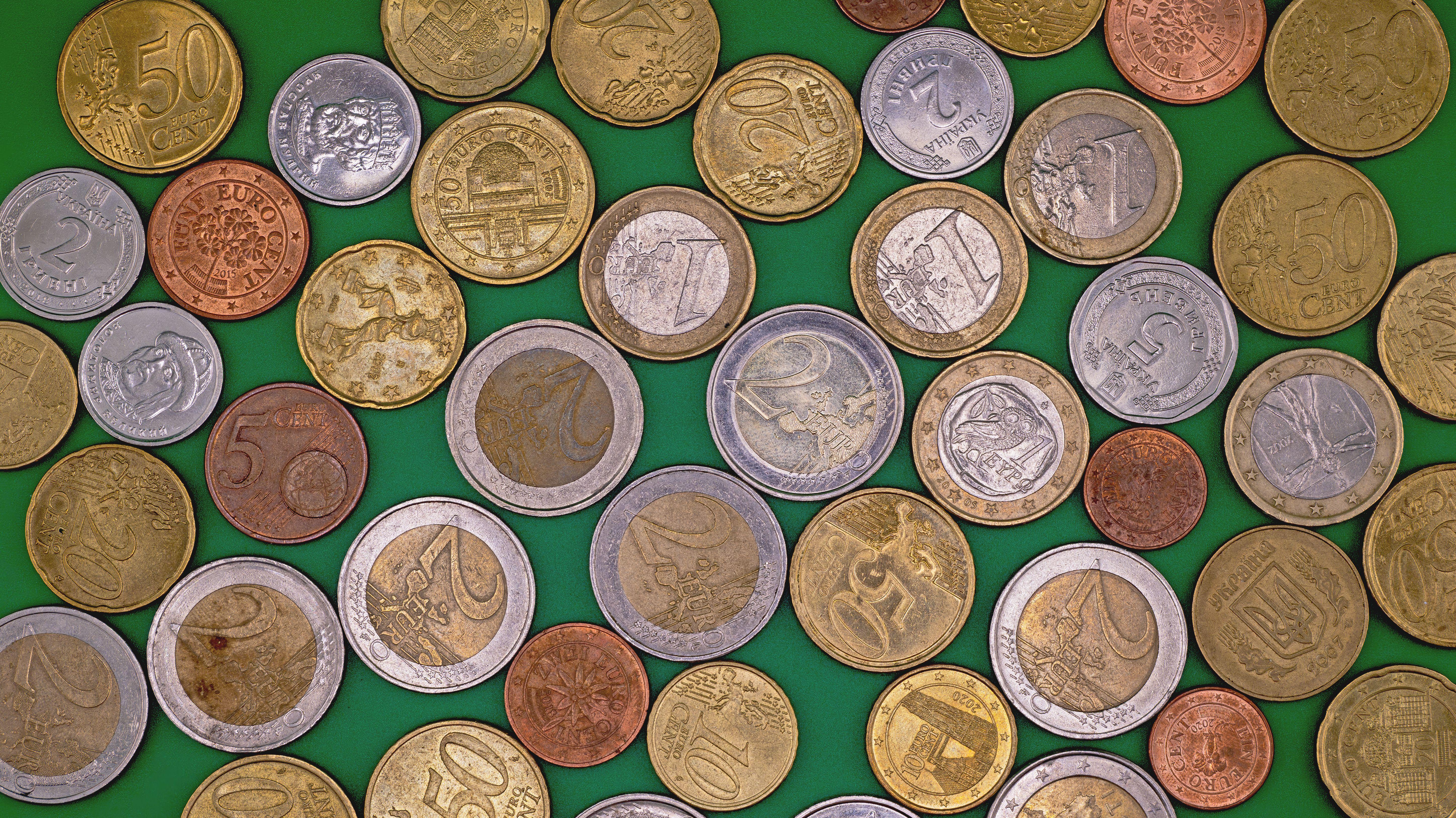 Assorted Euro coins spread on a vibrant green surface, showcasing different denominations and designs.