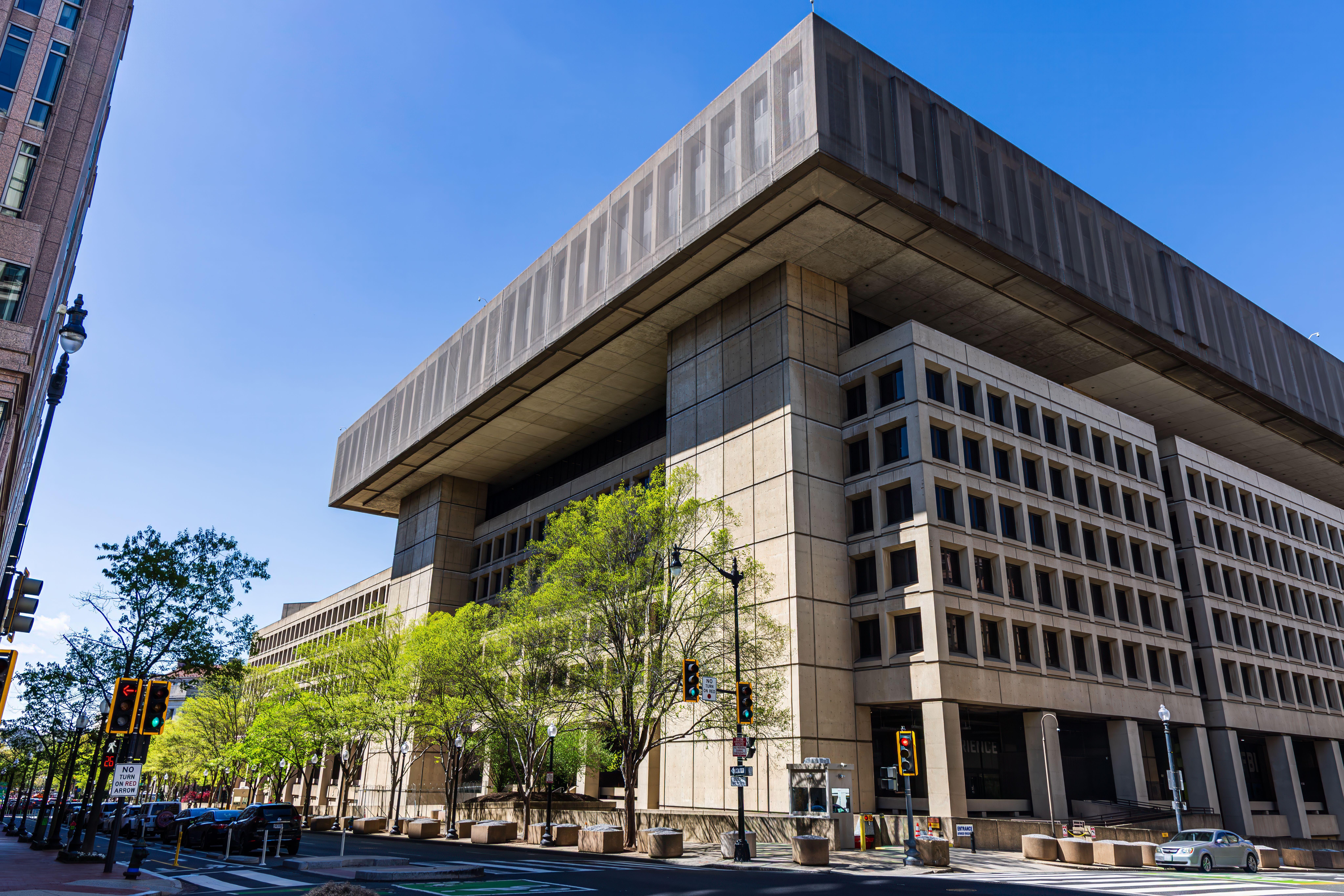 Photo of a modernist government building with a distinct overhang, taken on a sunny day with clear blue skies.