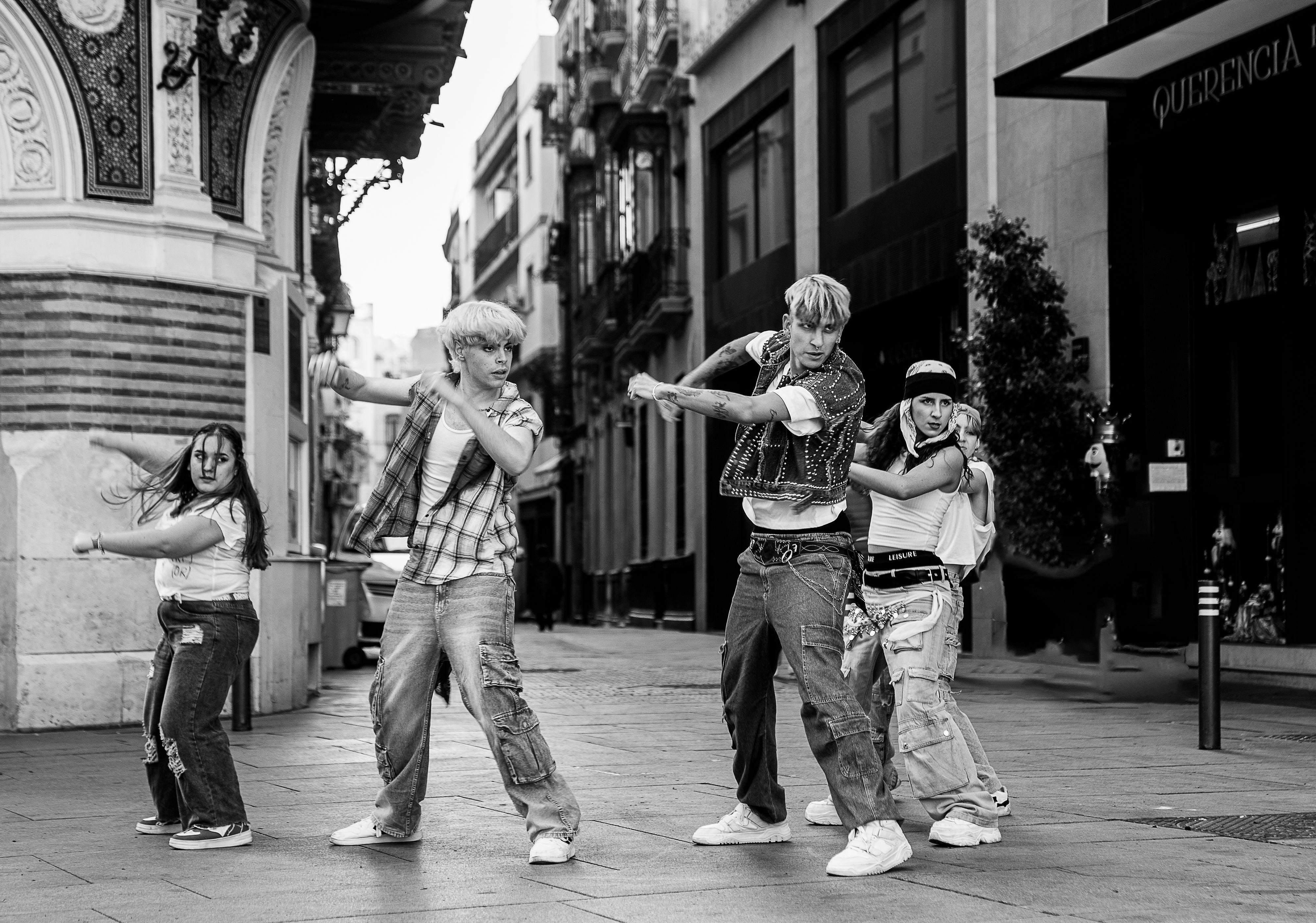 Four street dancers performing energetically in a historic street of Seville, Spain.