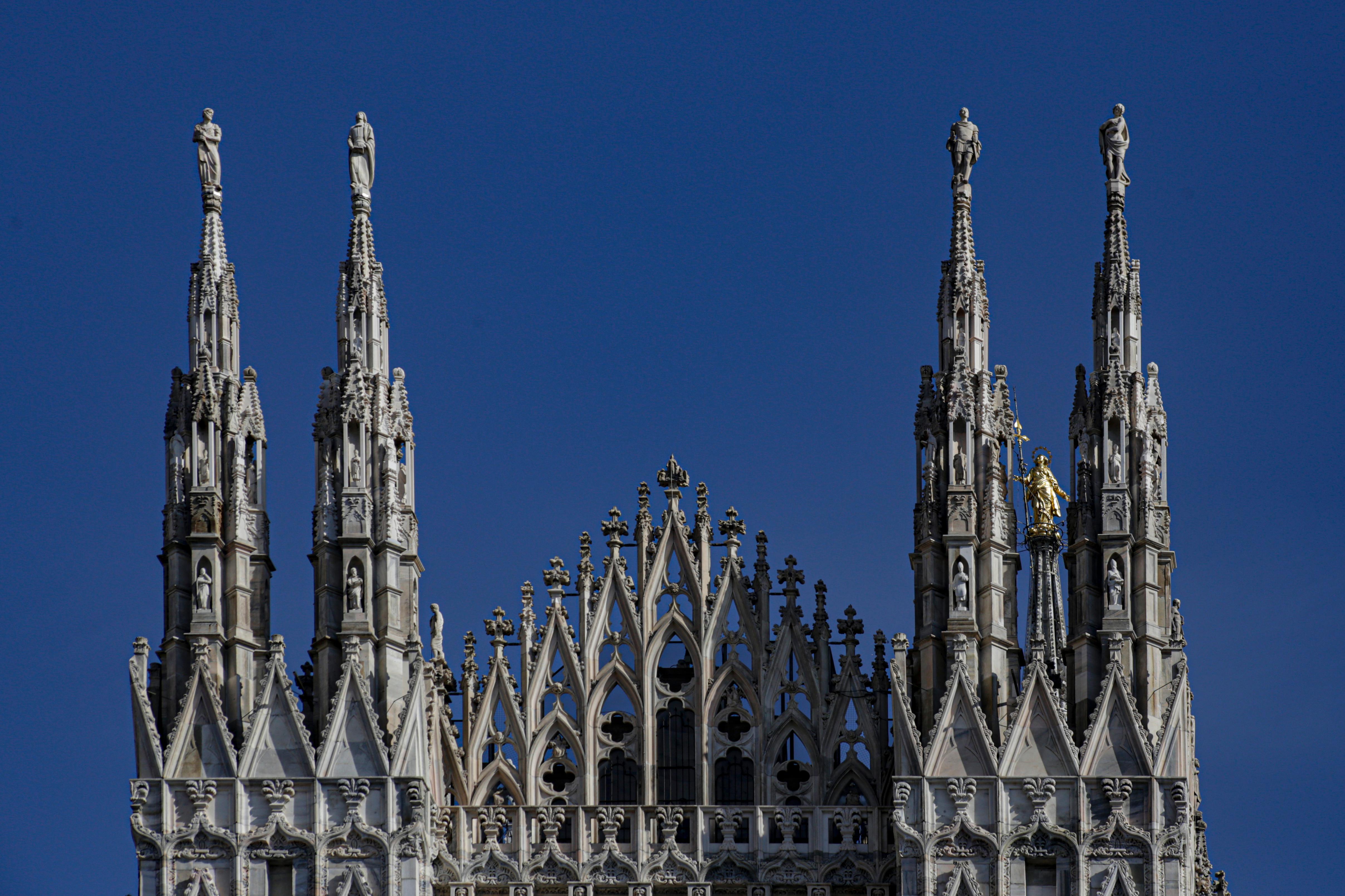 Close-up of the ornate spires of Milan Cathedral against a clear blue sky.