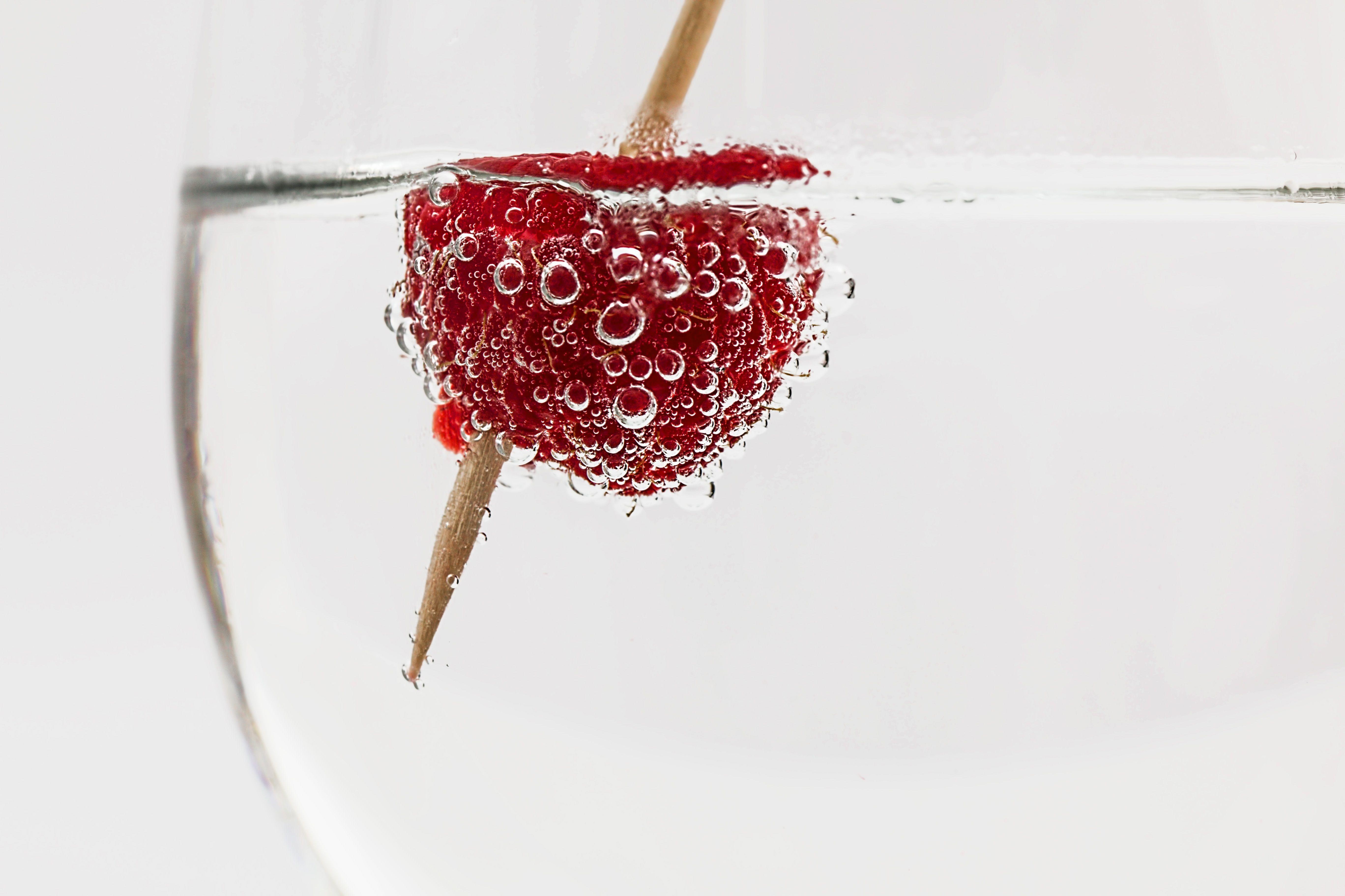 Close-up of a raspberry in sparkling water, highlighting freshness and effervescence.