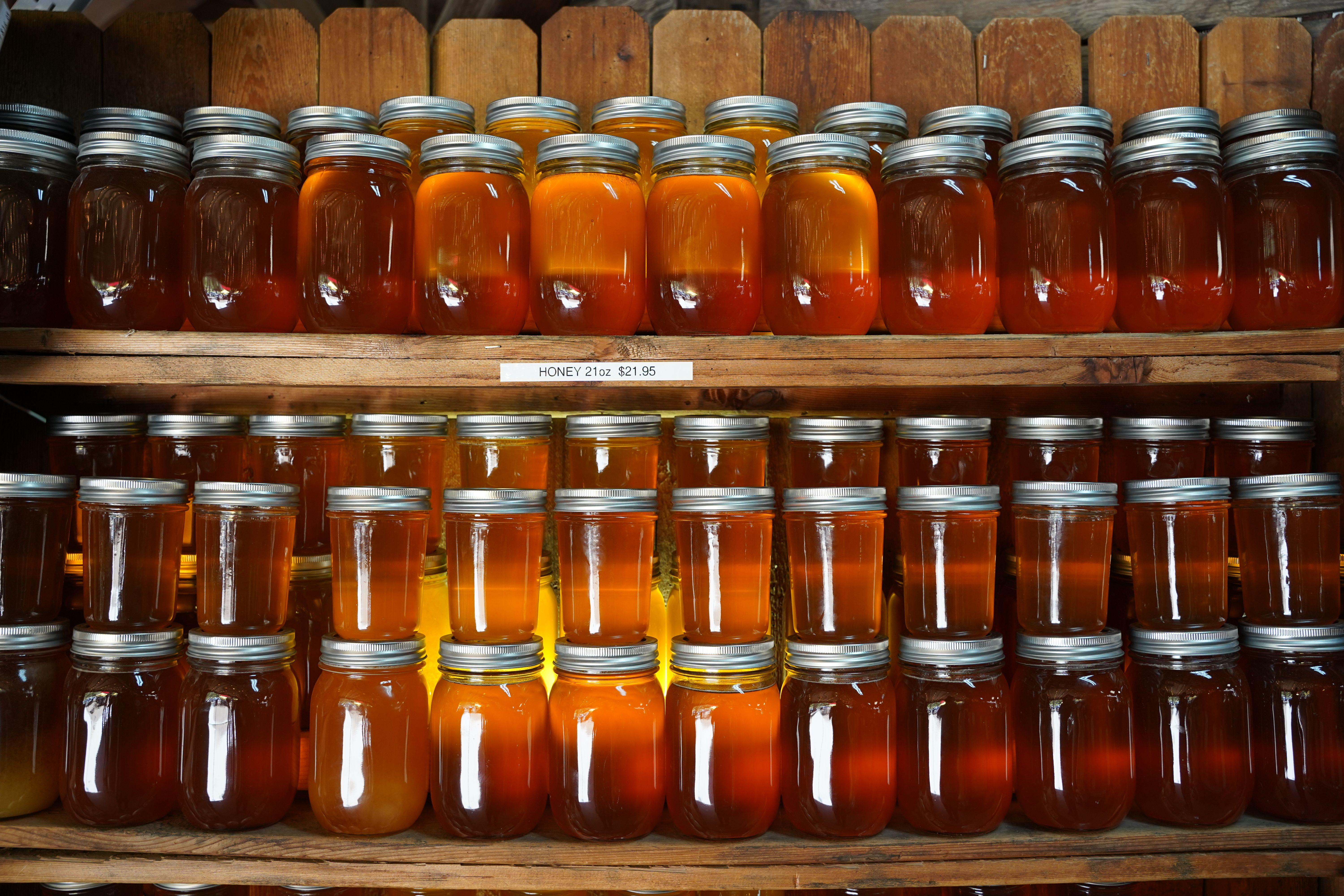Dozens of honey jars on shelves in a rustic setting create a warm, inviting display.