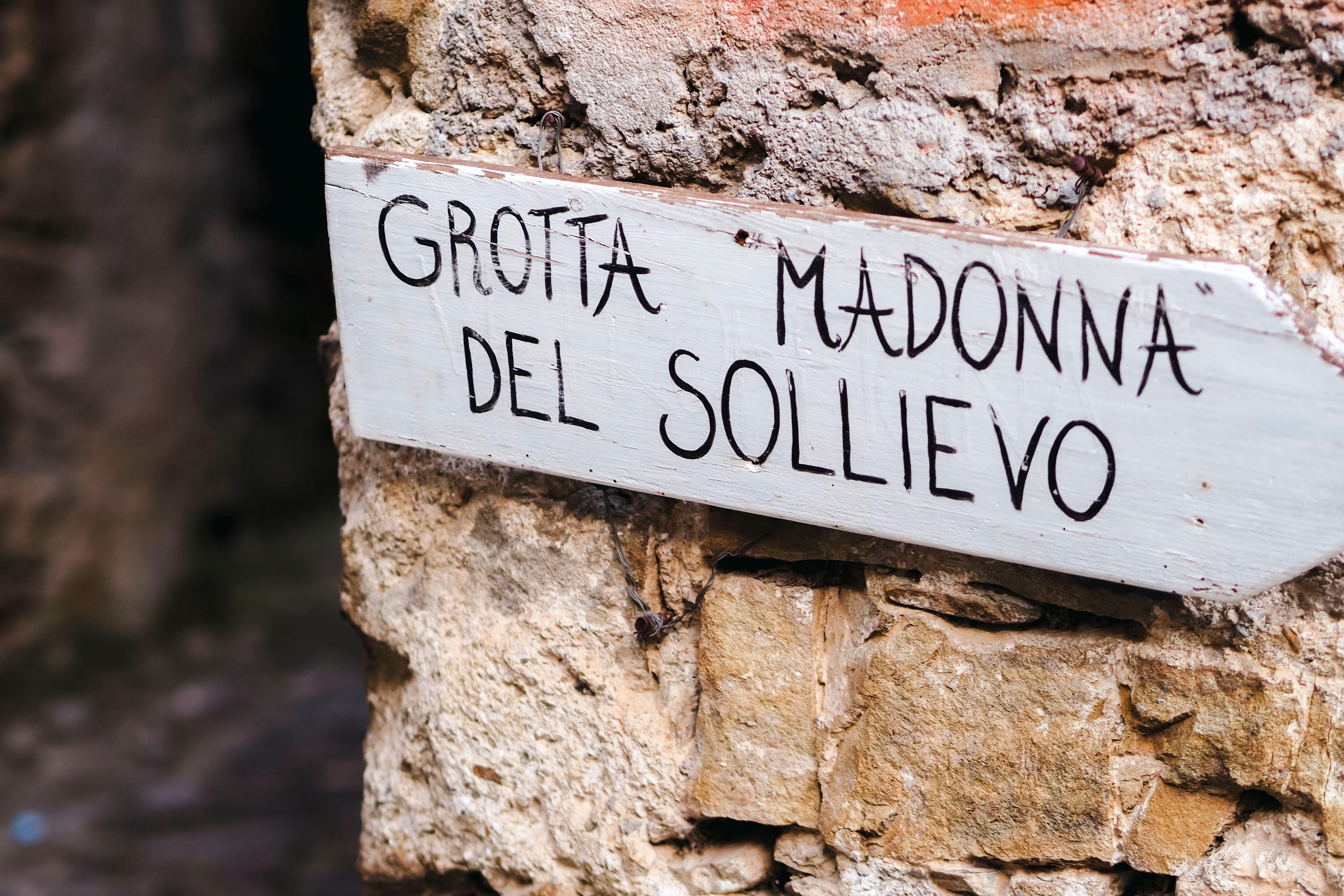 A rustic sign on a stone wall at Grotta Madonna del Sollievo in Provence-Alpes-Côte d'Azur.