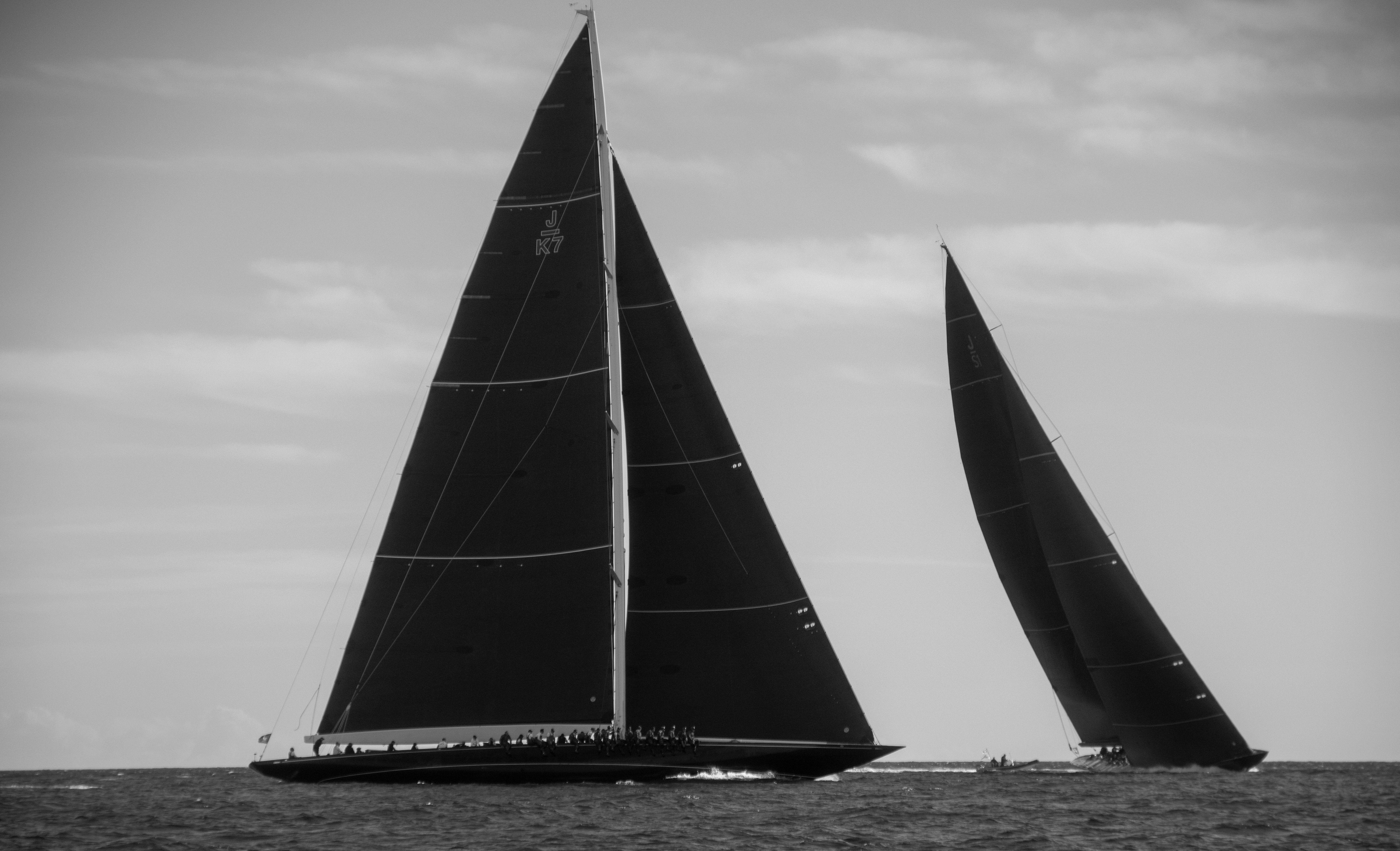 Monochrome image of two elegant sailboats racing on open waters with sleek designs.