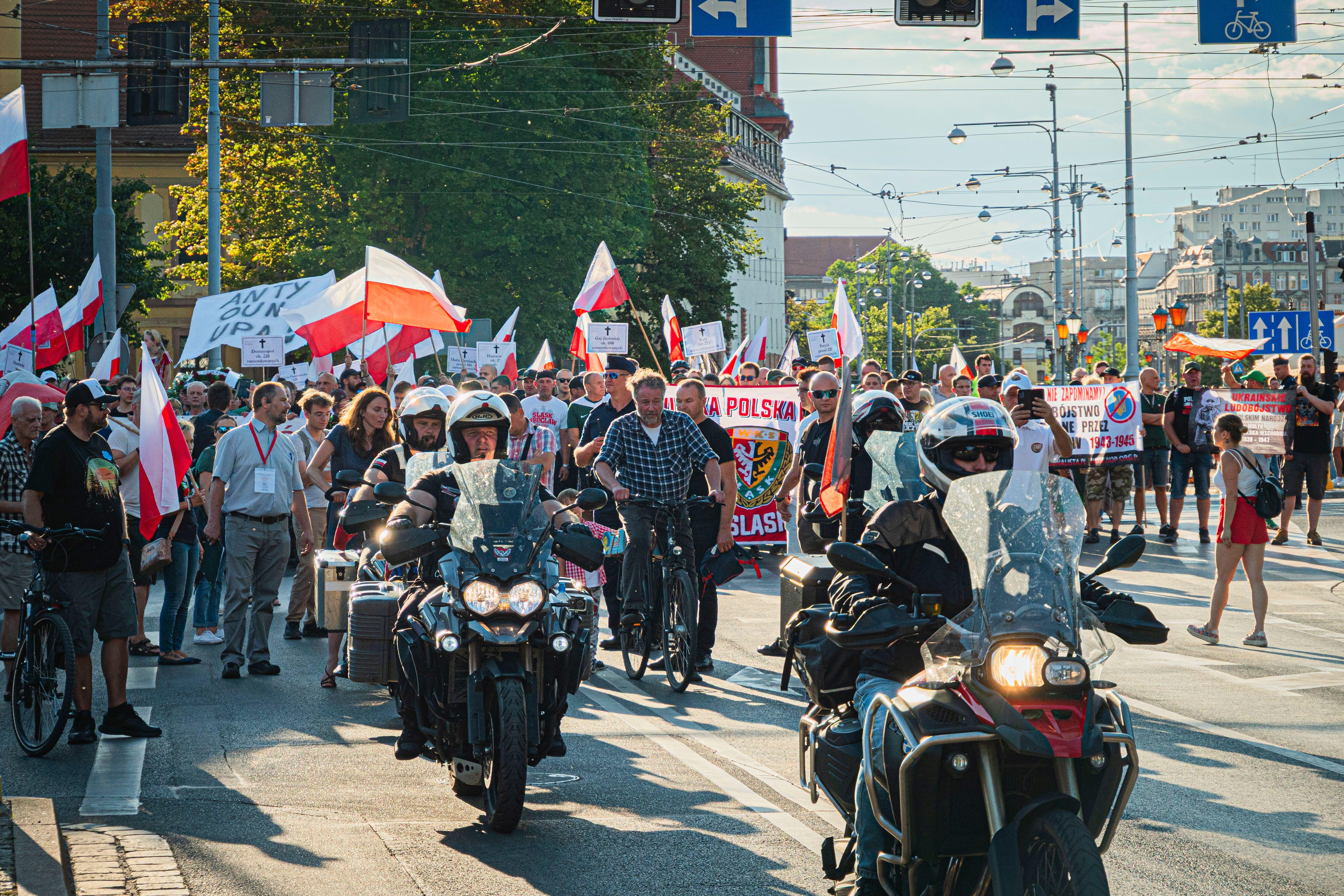 People marching in Wrocław, Poland, commemorating historical events with flags and signs.