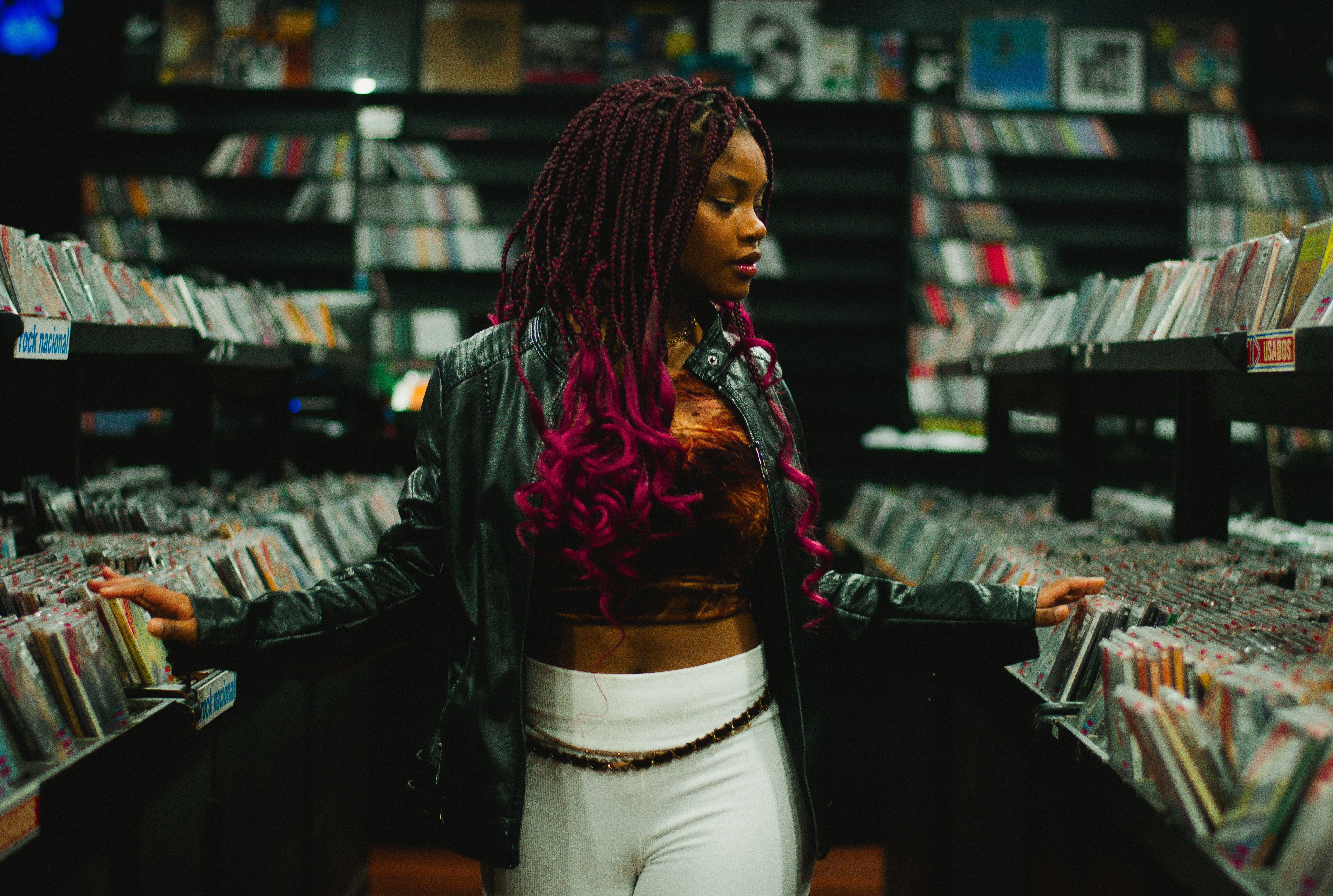 Stylish young woman exploring rows of vinyl records in a vibrant music store.