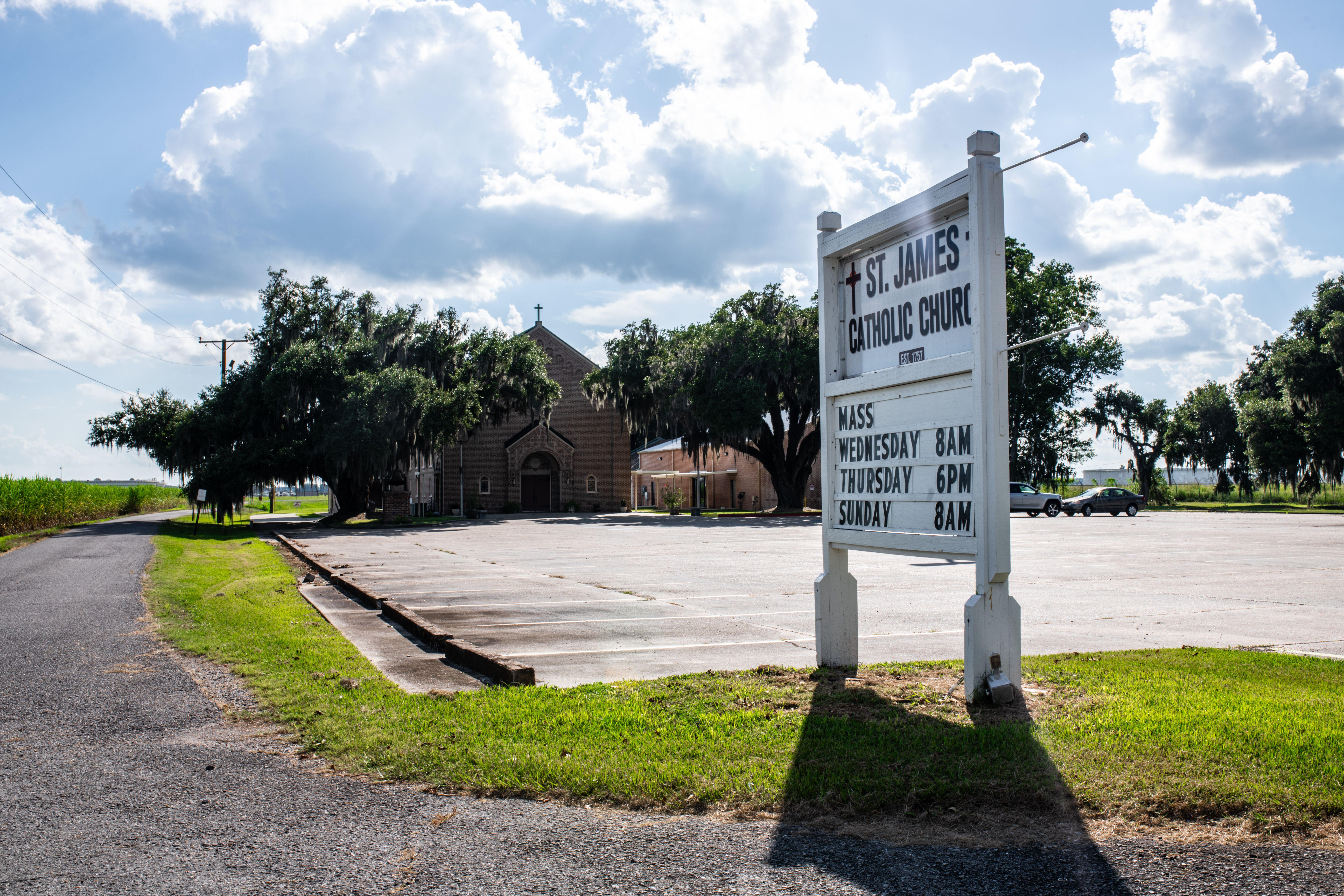 St. James Catholic Church with signage in a rural setting, captured under a bright sunny sky.