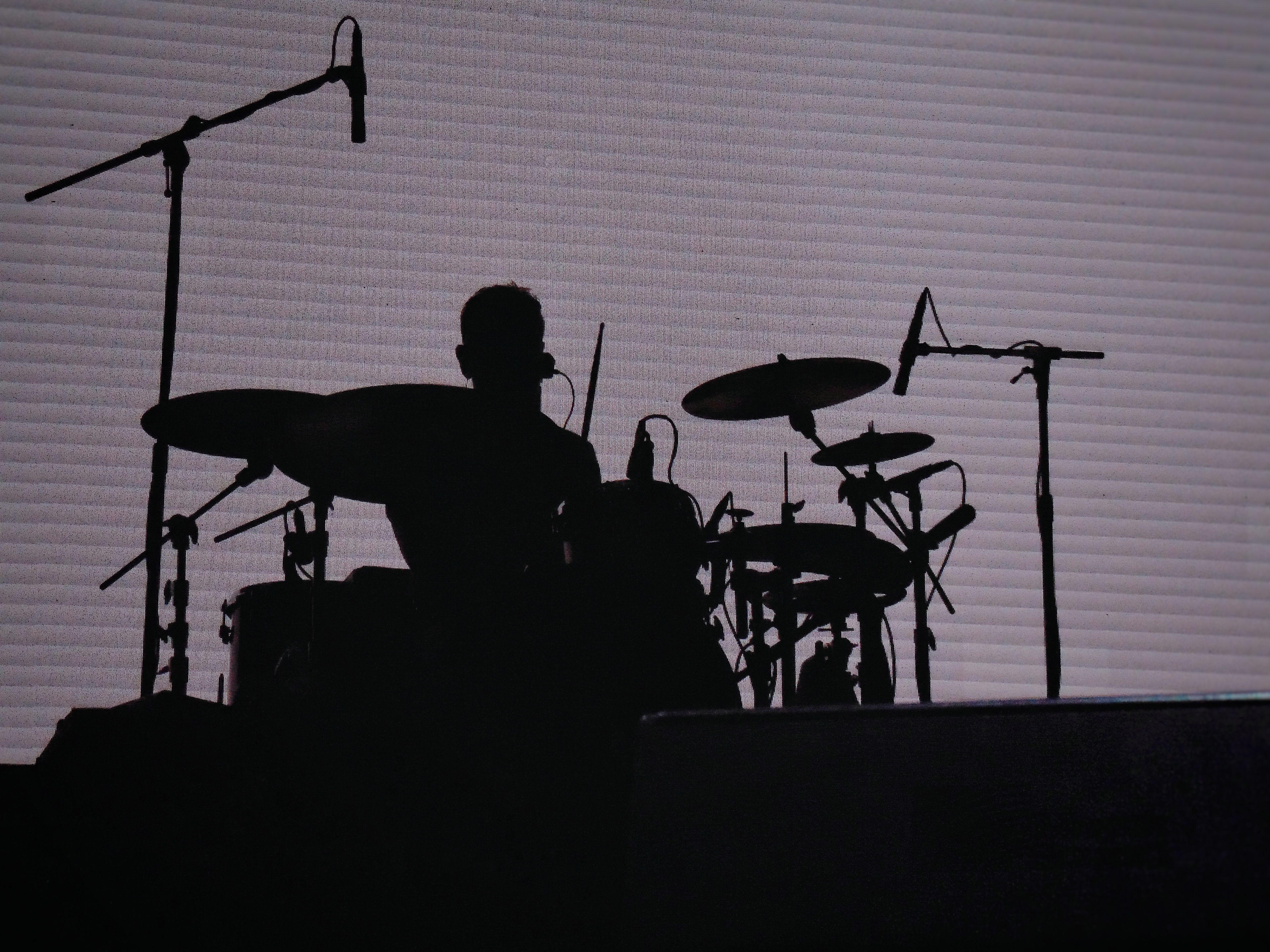 Dramatic silhouette of a drummer performing on stage, highlighting music and performance themes.