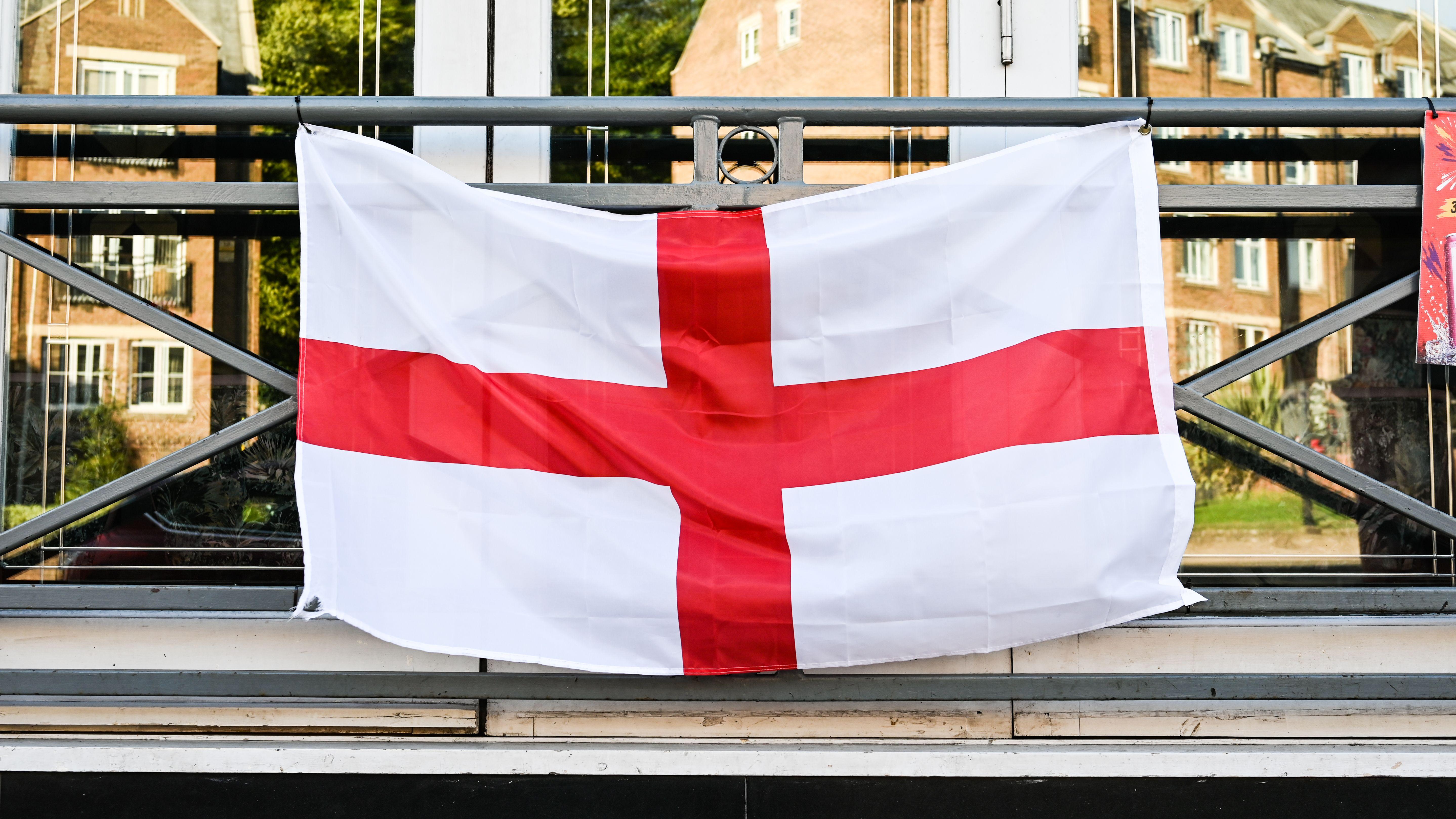 A St George's Cross flag displayed on a building facade, reflecting urban English patriotism.