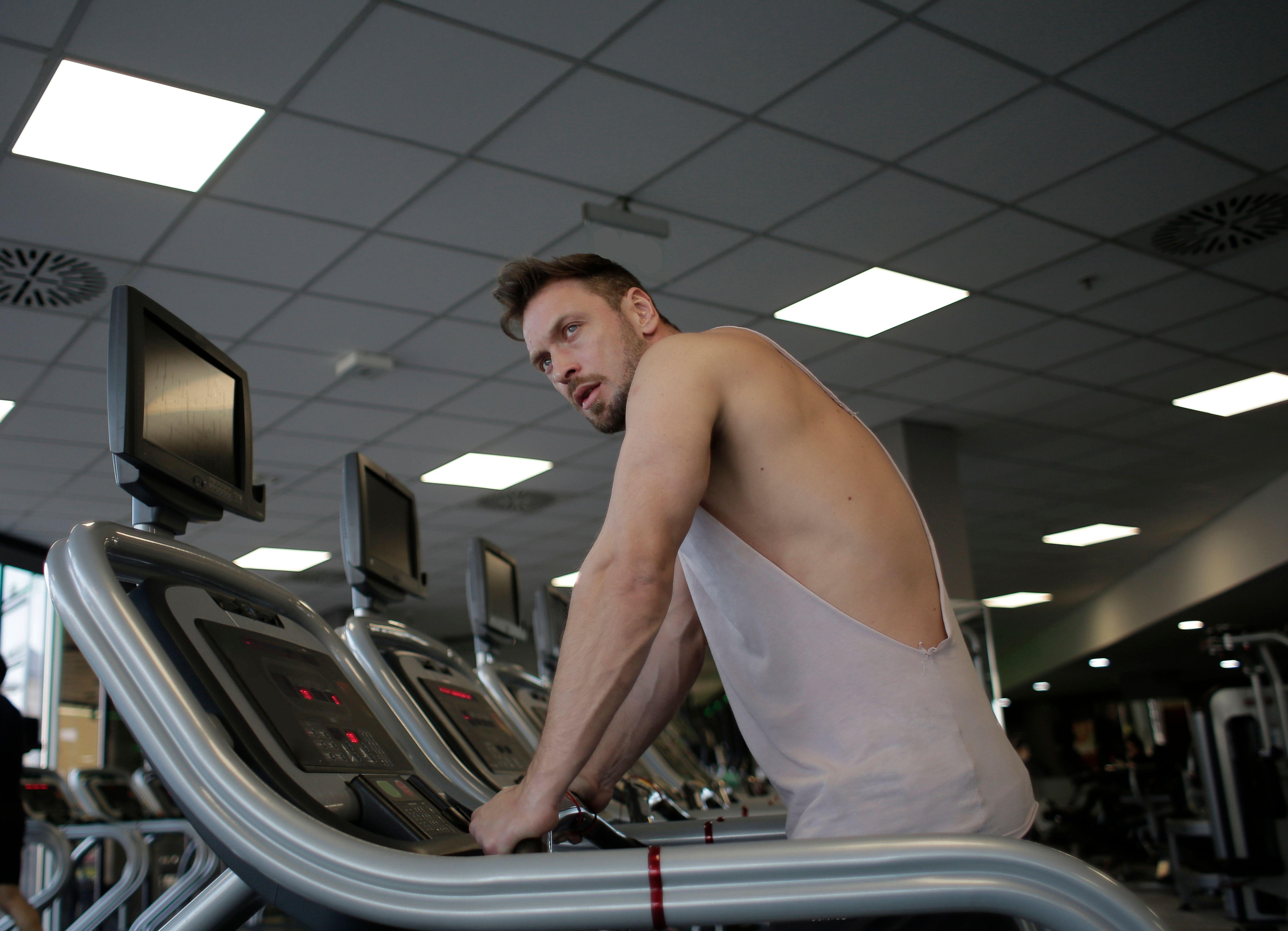 A focused man exercising on a treadmill in a modern gym setting, showcasing dedication and fitness.