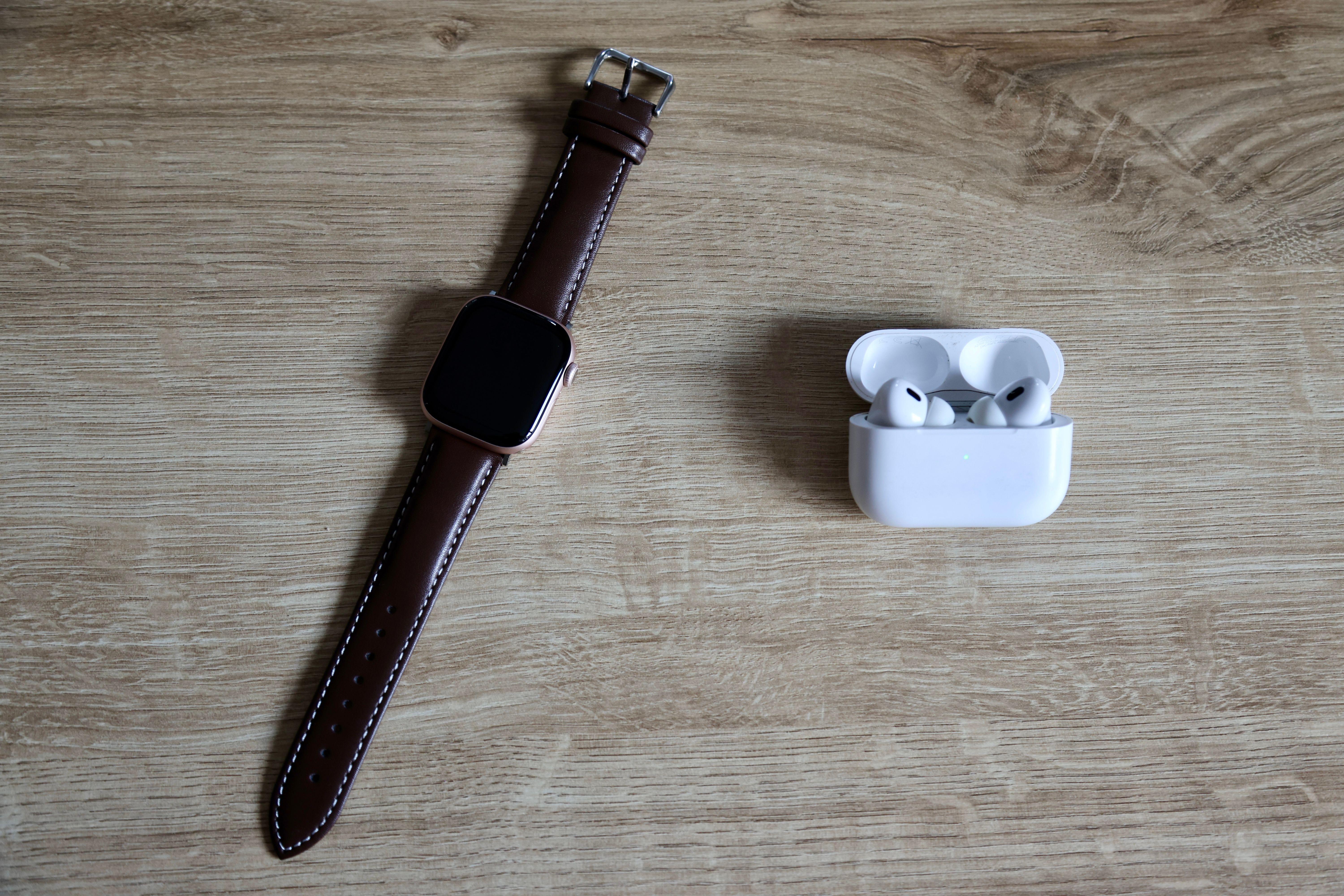 Flat lay of a smartwatch and wireless earbuds on a wooden surface, emphasizing modern EDC essentials.