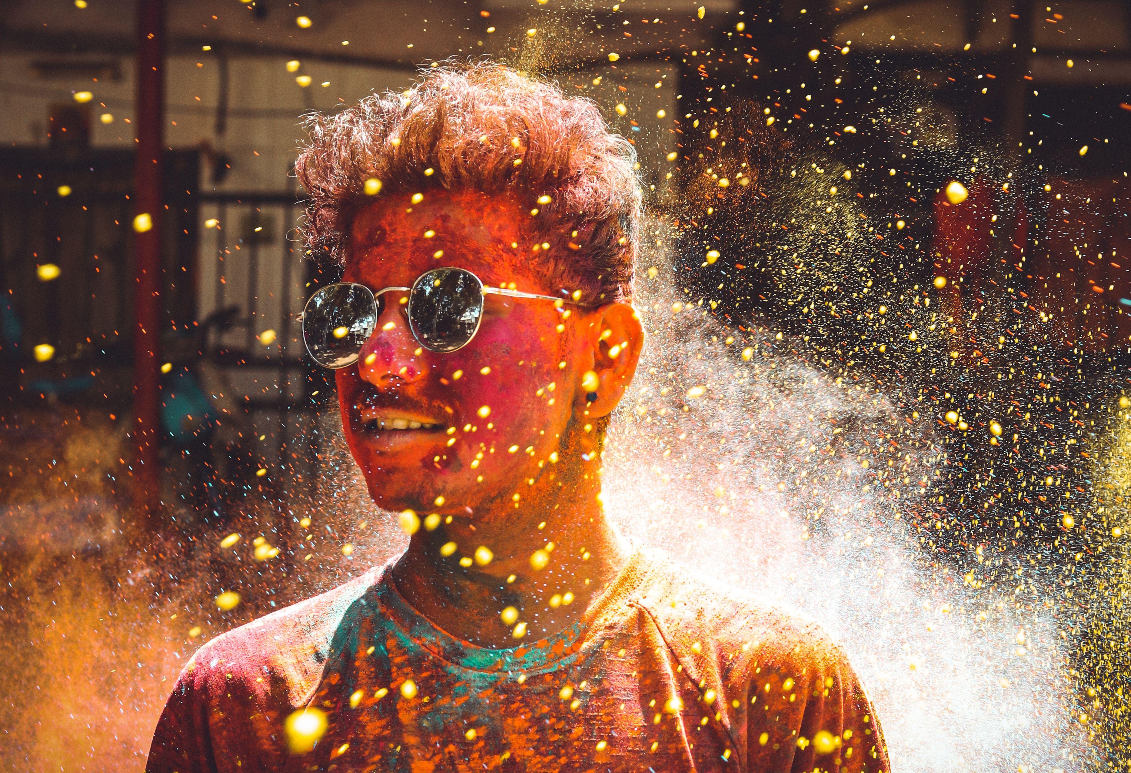 A man celebrates Holi with colorful powder in Mumbai, capturing the vibrant spirit of the festival.