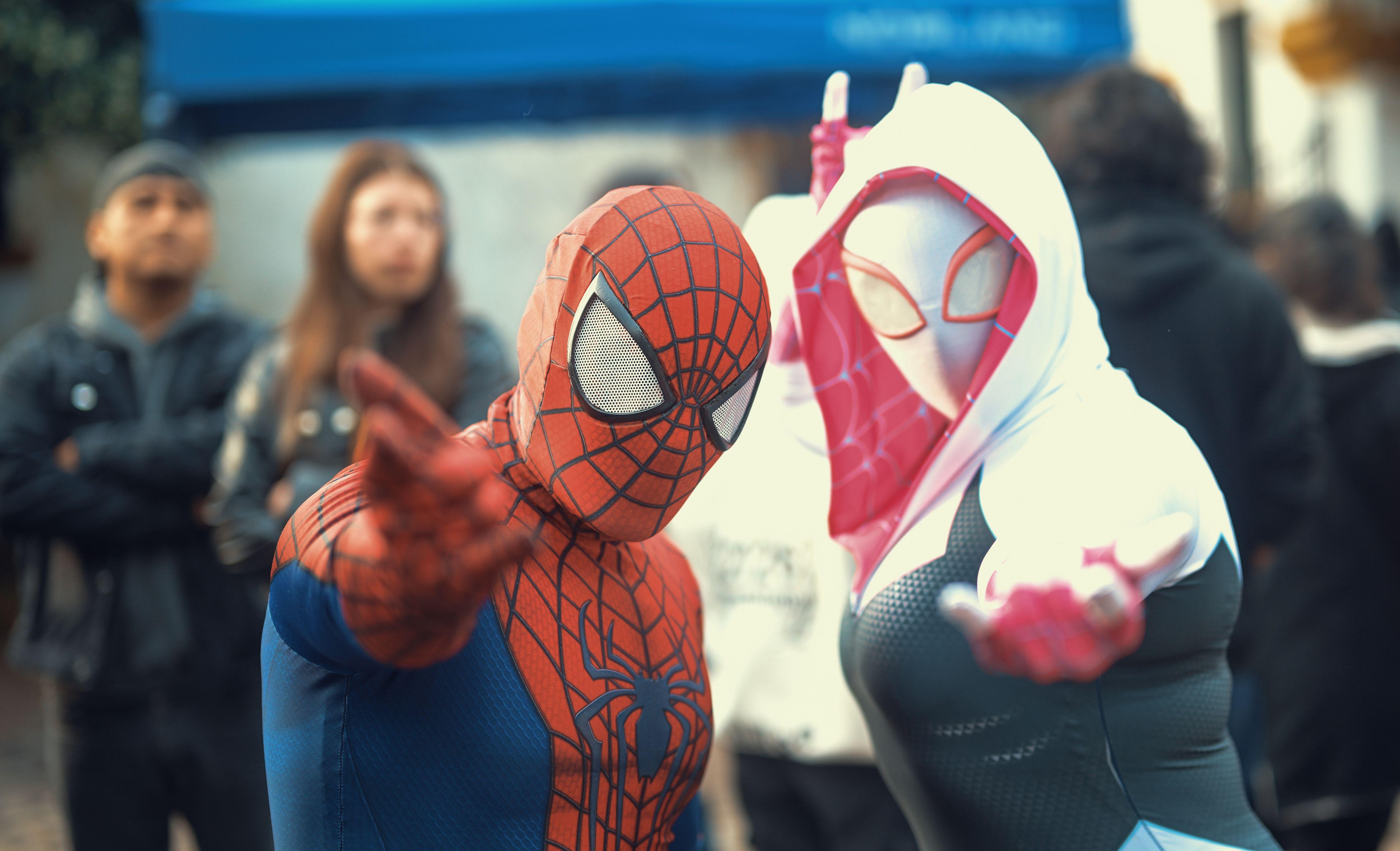 Cosplayers dressed as Spider-Man and Spider-Woman in a crowded street in Buenos Aires.