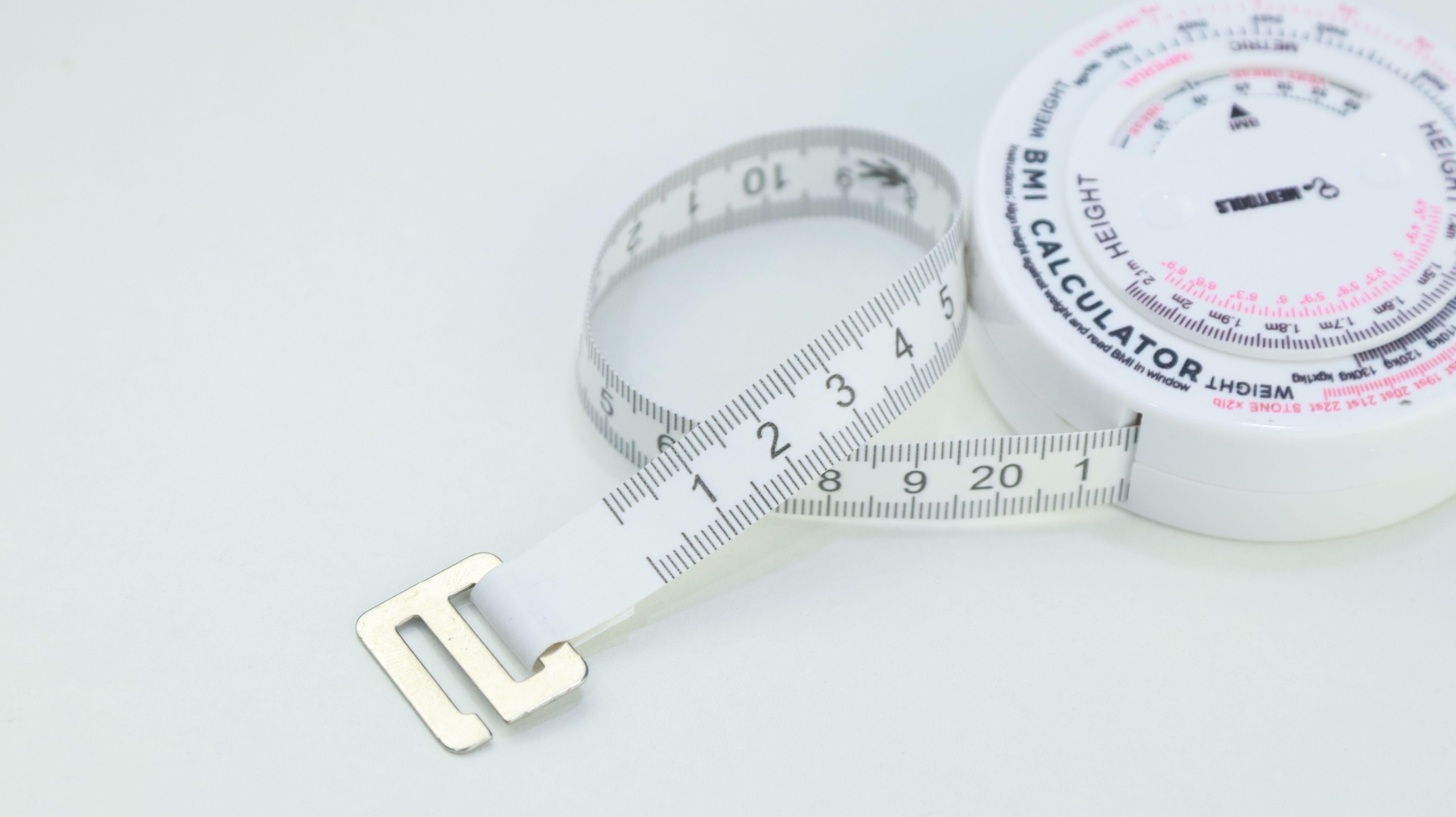 Close-up of a BMI calculator and measuring tape, essential for health assessments.