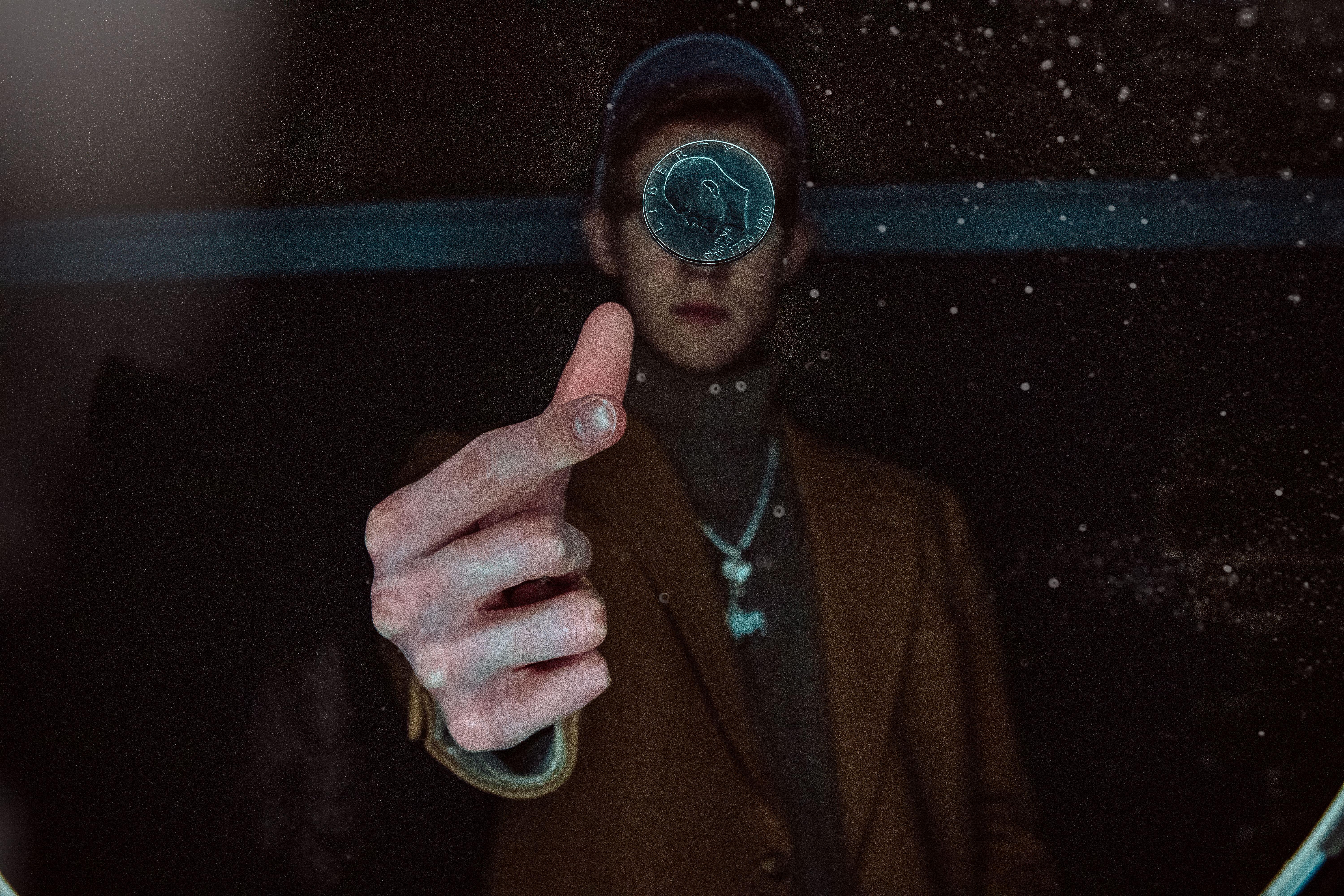 A person dramatically flipping a coin in a dimly lit environment, capturing motion and focus.