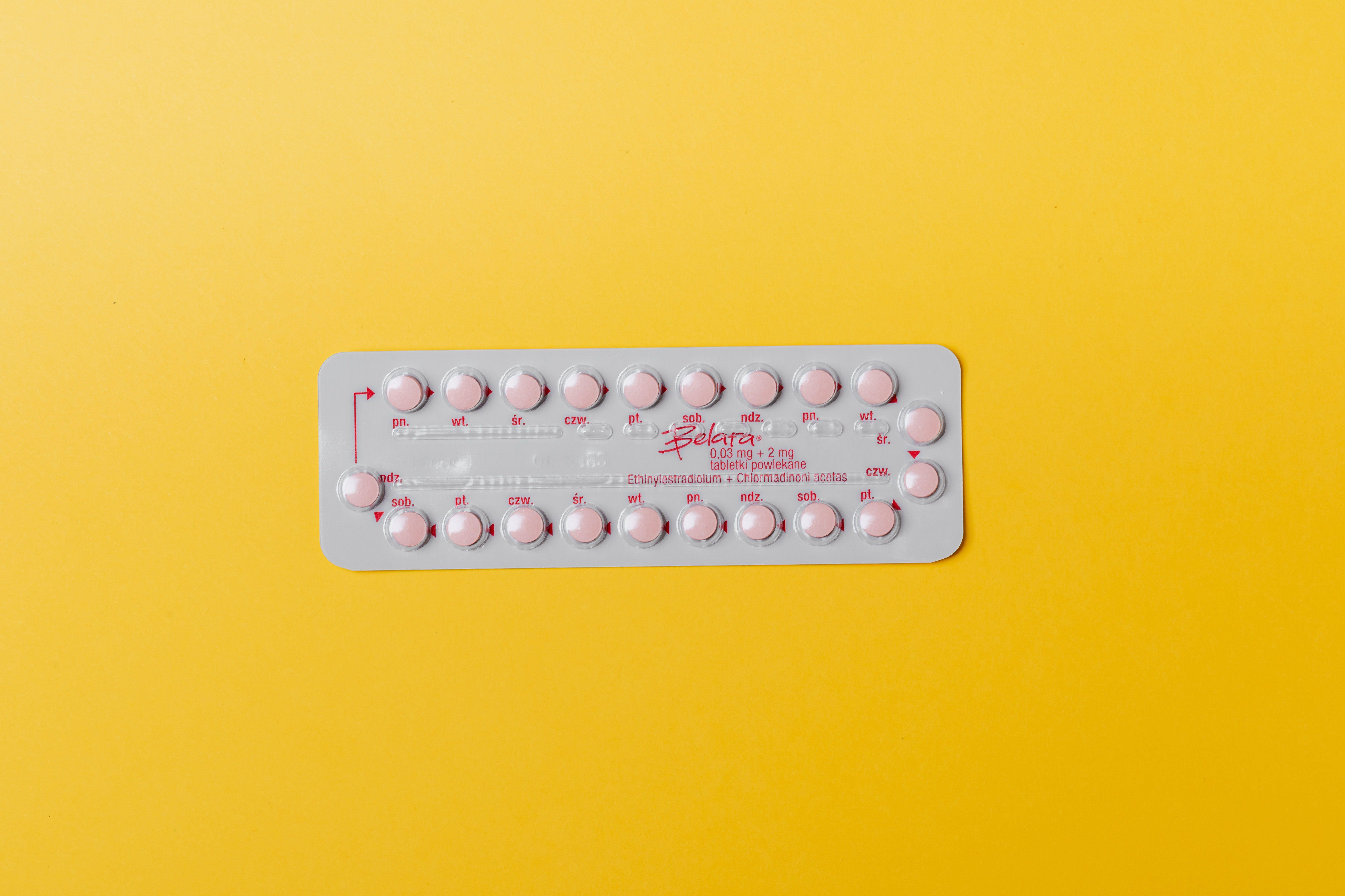 Close-up of a blister pack of pink pills on a vivid yellow background for medication concept.