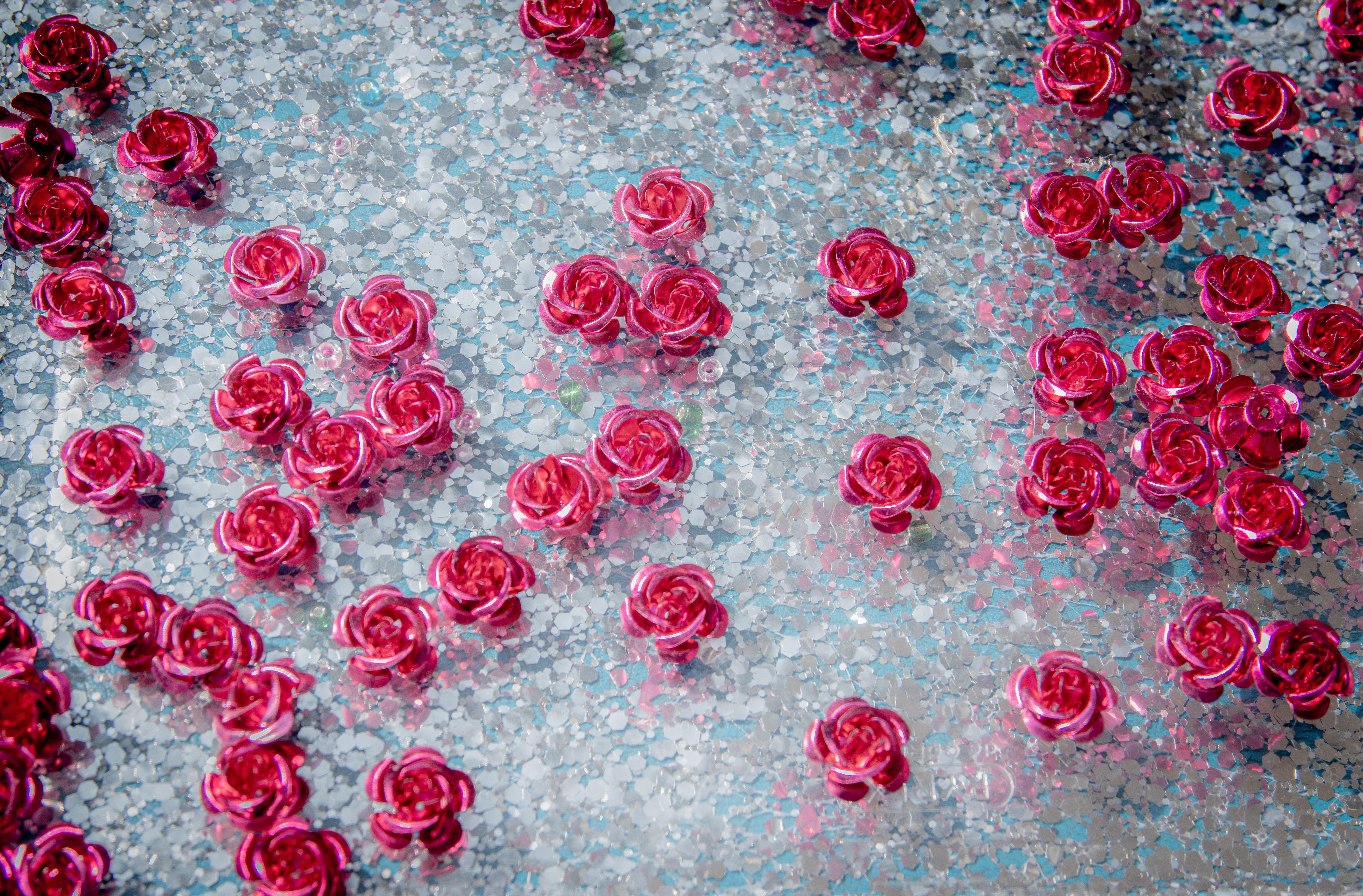 Close-up of decorative pink rose sequins scattered on a glittery background, creating a vibrant and festive look.