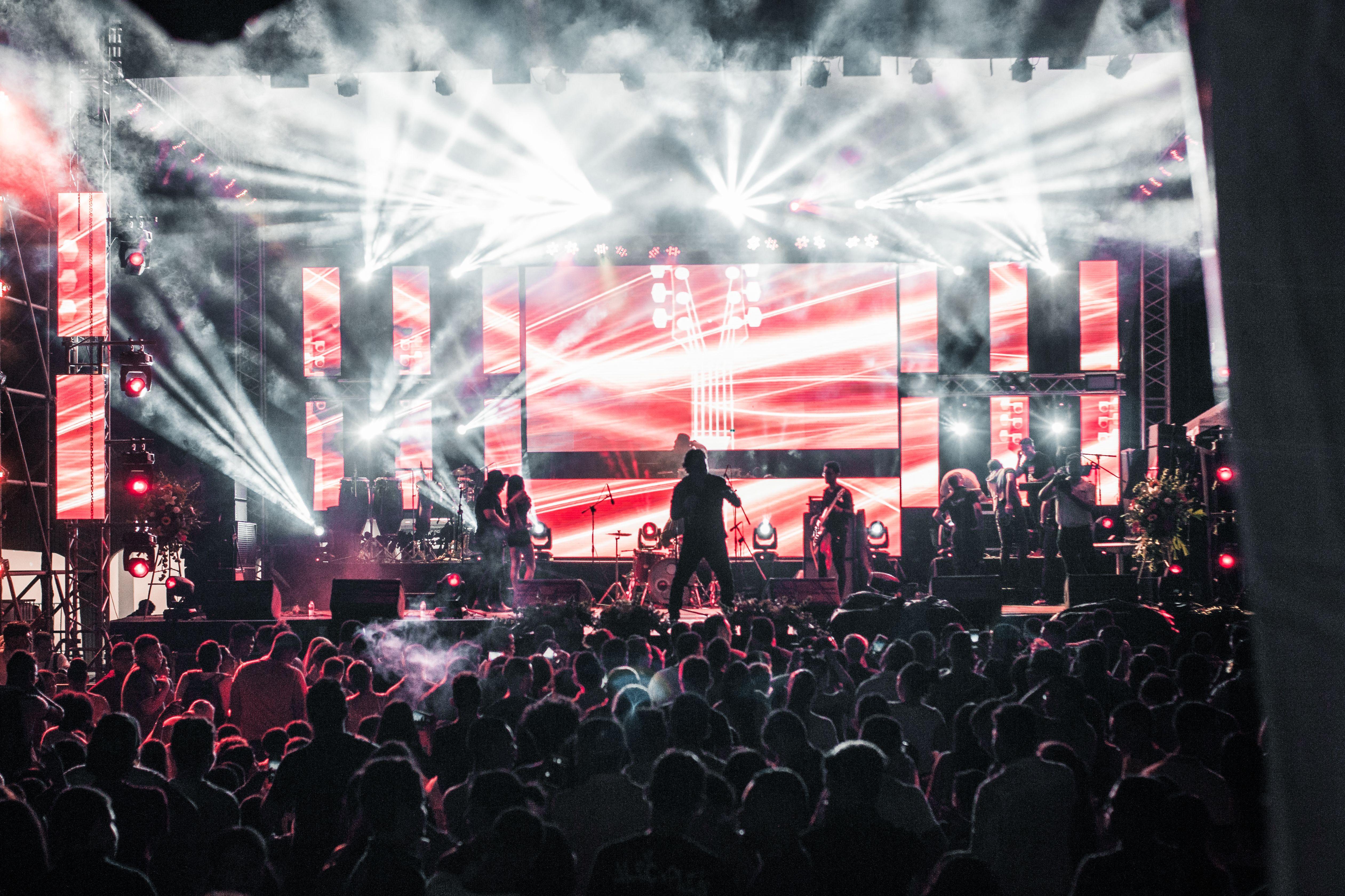 Energetic live music concert featuring performers on a vibrant stage, captivating a large audience.