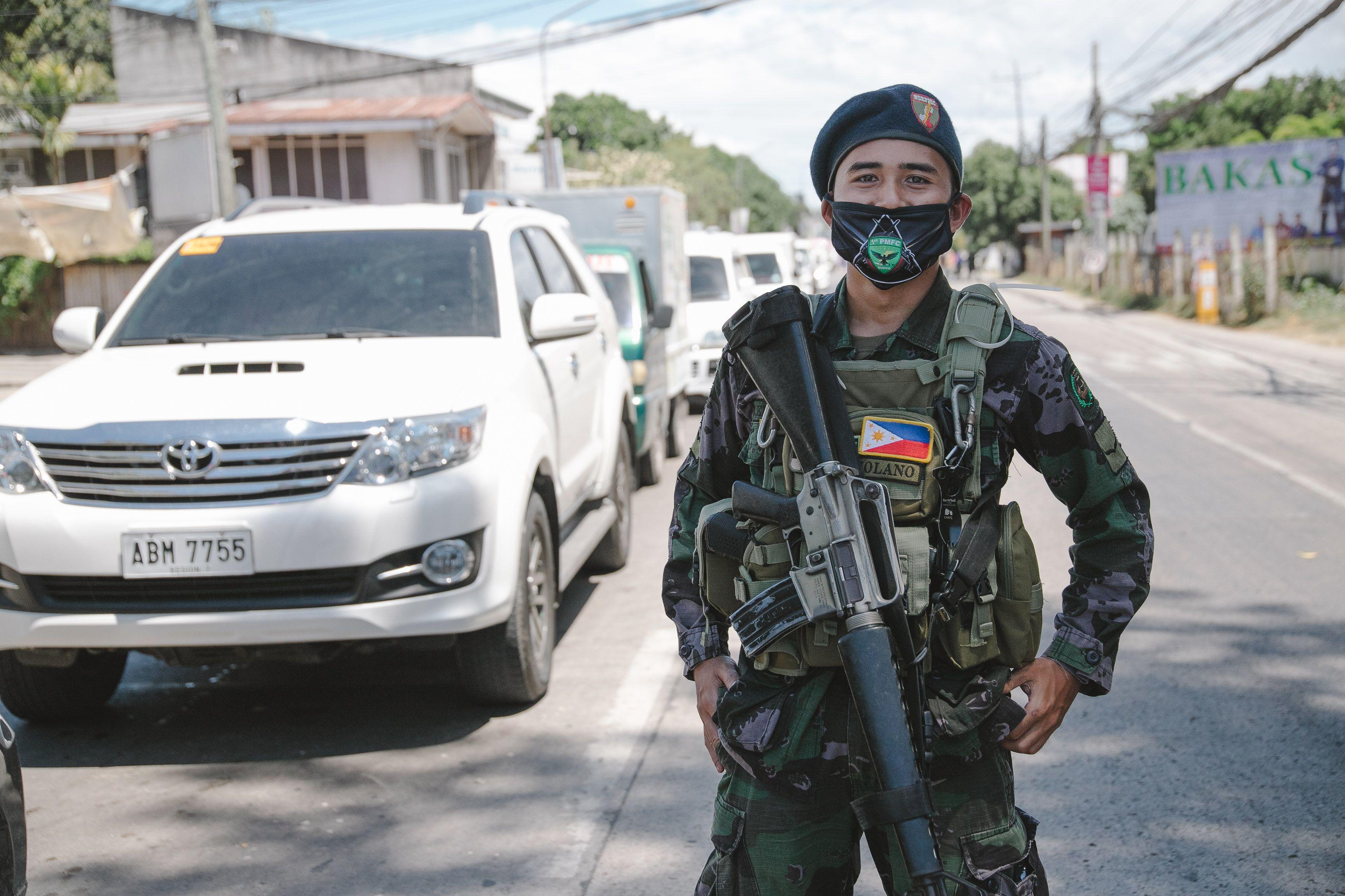 A Philippine soldier in uniform and mask standing on a city street, showcasing military presence.