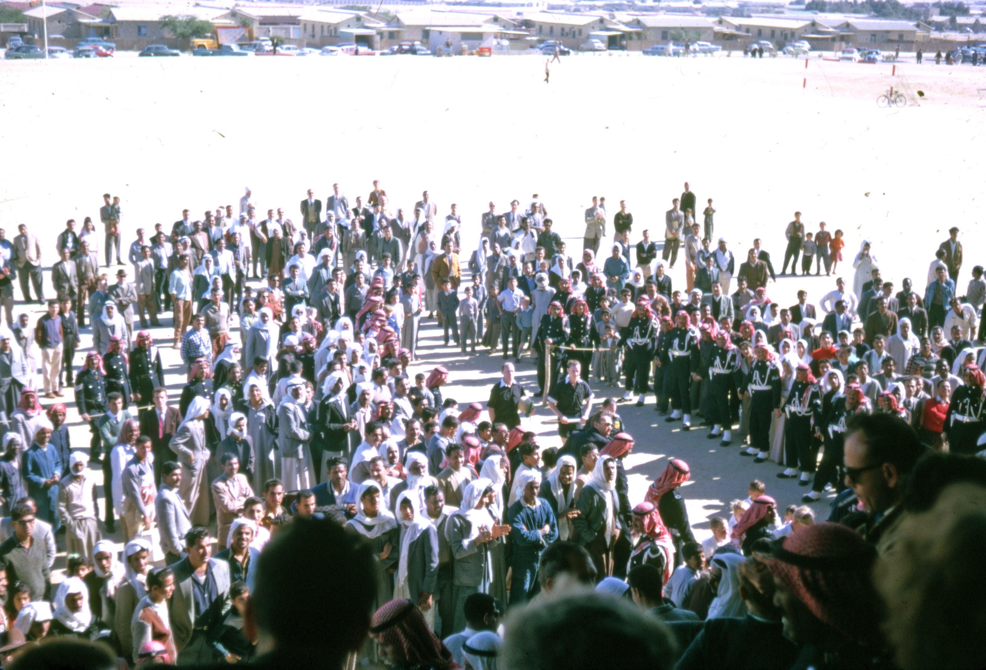 A large crowd gathers outdoors under sunny conditions in Saudi Arabia.