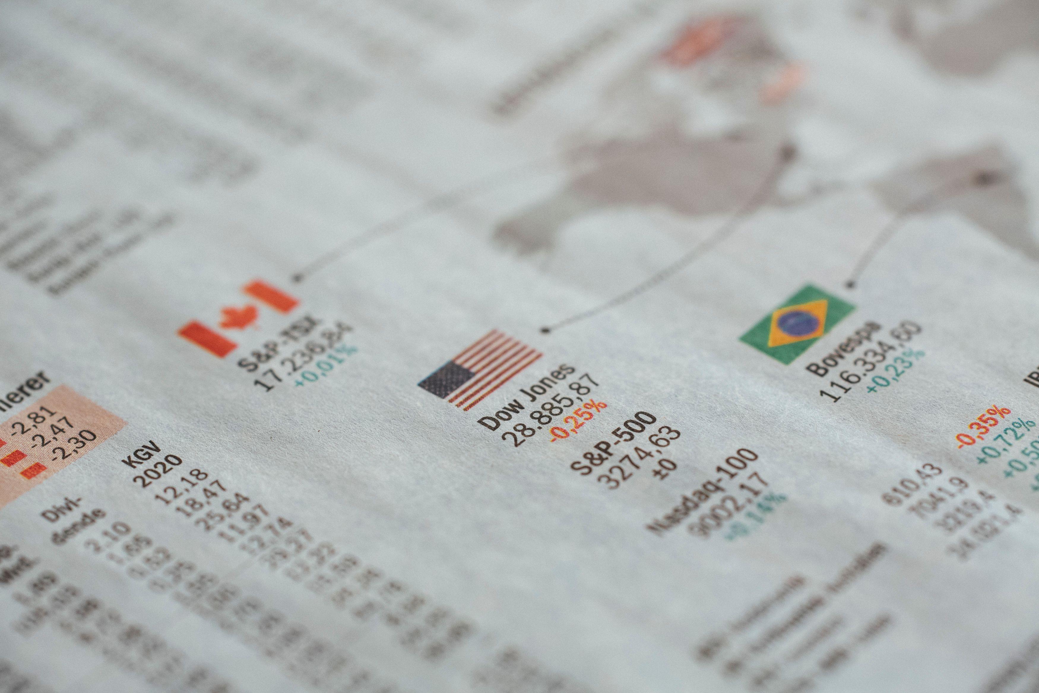 Detailed close-up of a newspaper displaying global financial market statistics and country flags.