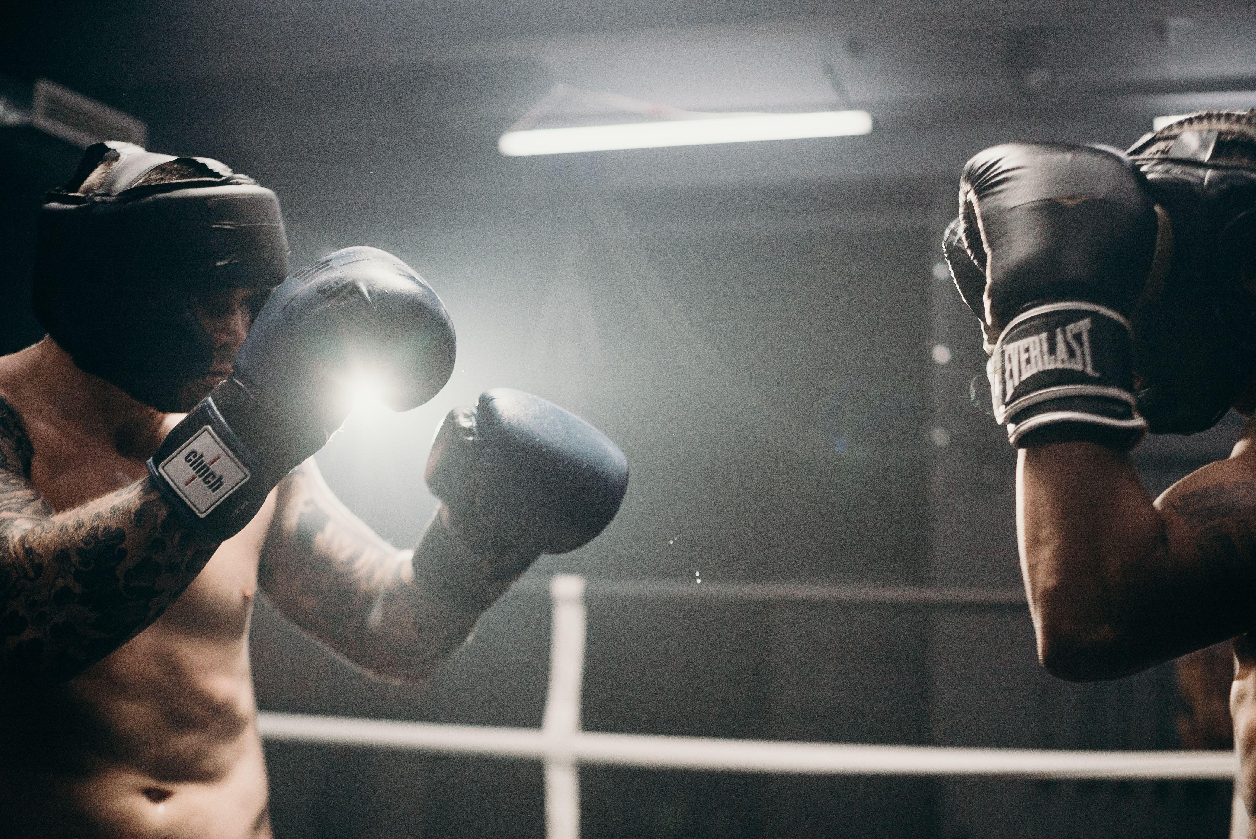 Two men sparring in a dimly lit gym, showcasing intense boxing training and athleticism.