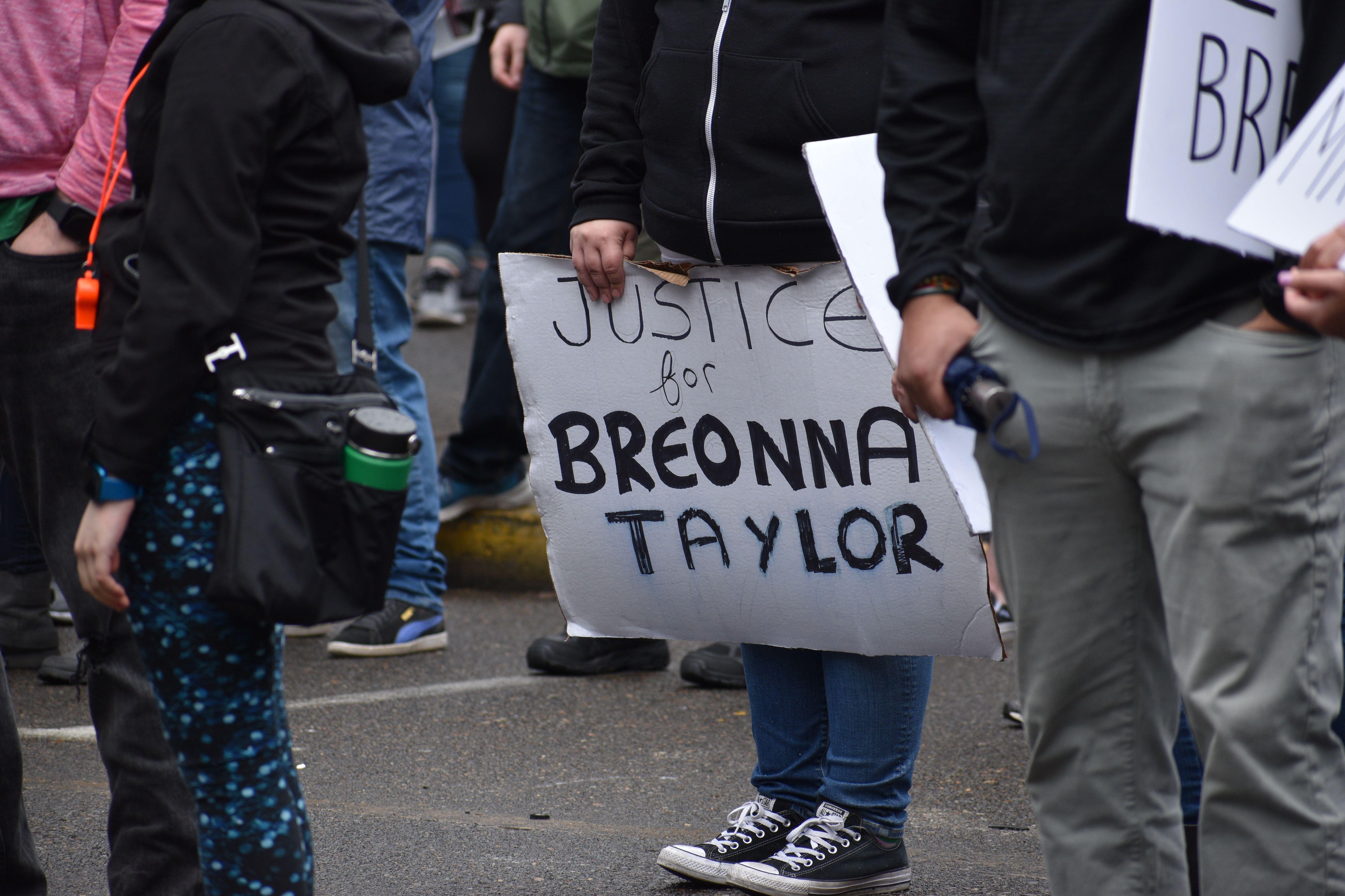A peaceful protest advocating justice for Breonna Taylor with participants holding signs outdoors.