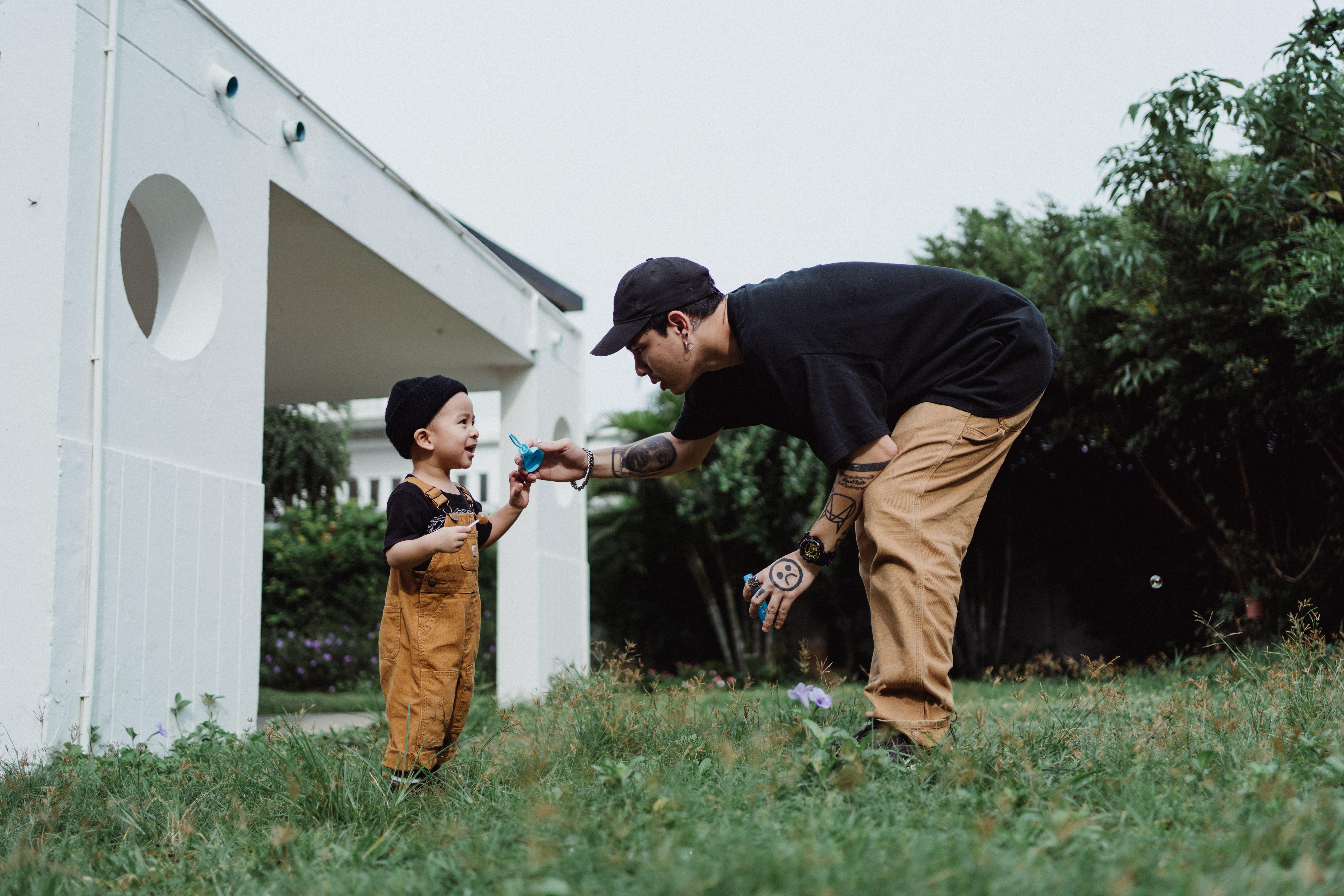 A joyful moment of a father and son playing with bubbles in a garden setting.