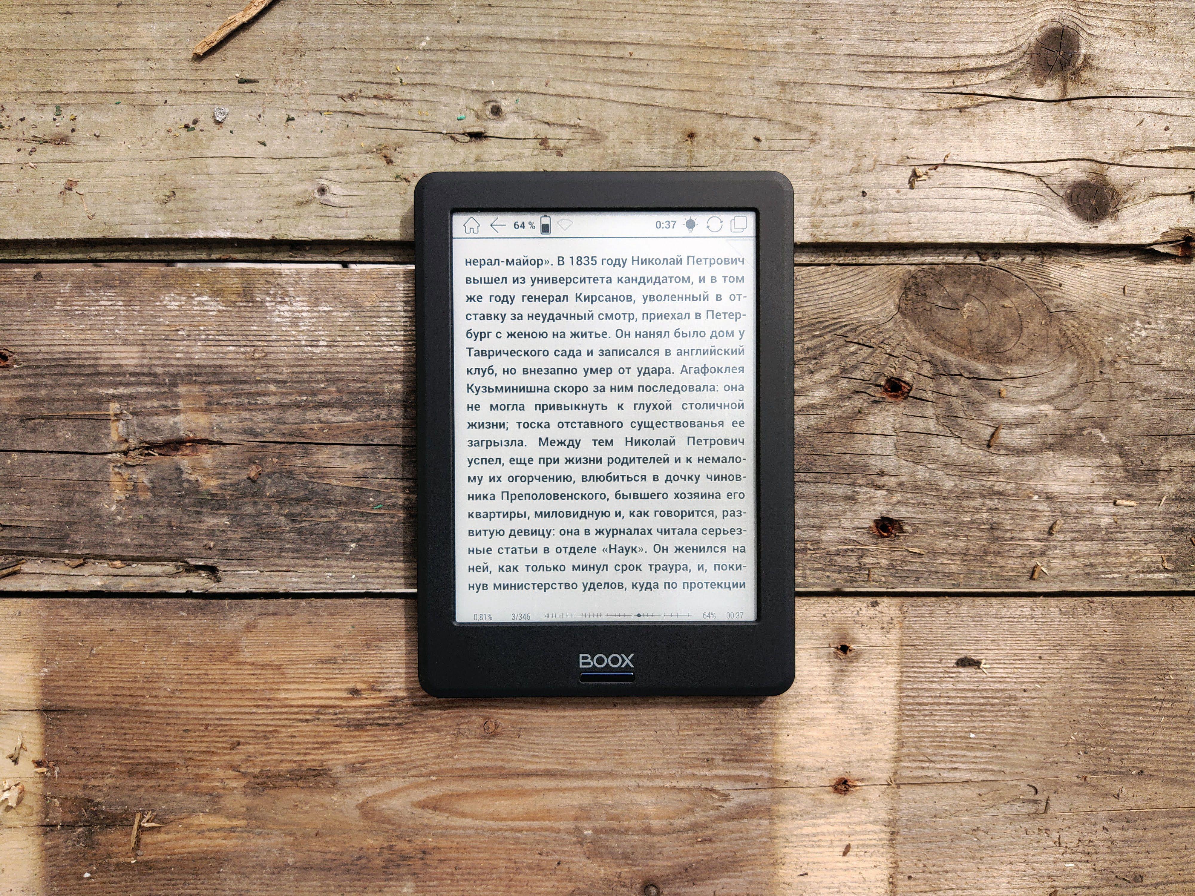 E-reader placed on a rustic wooden surface displaying text in Russian.