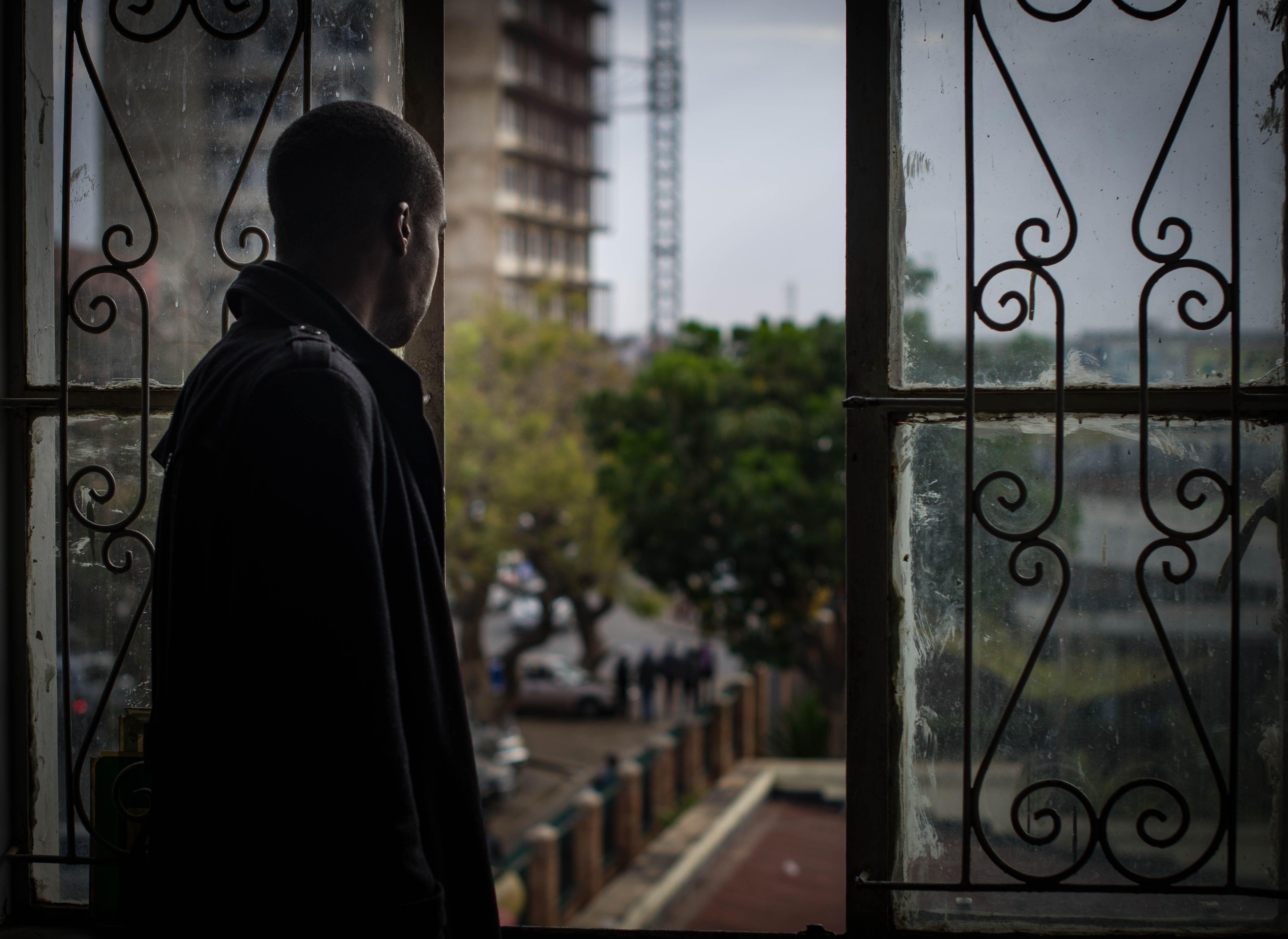 A man gazes out a window, capturing a thoughtful moment in Lusaka's urban landscape.