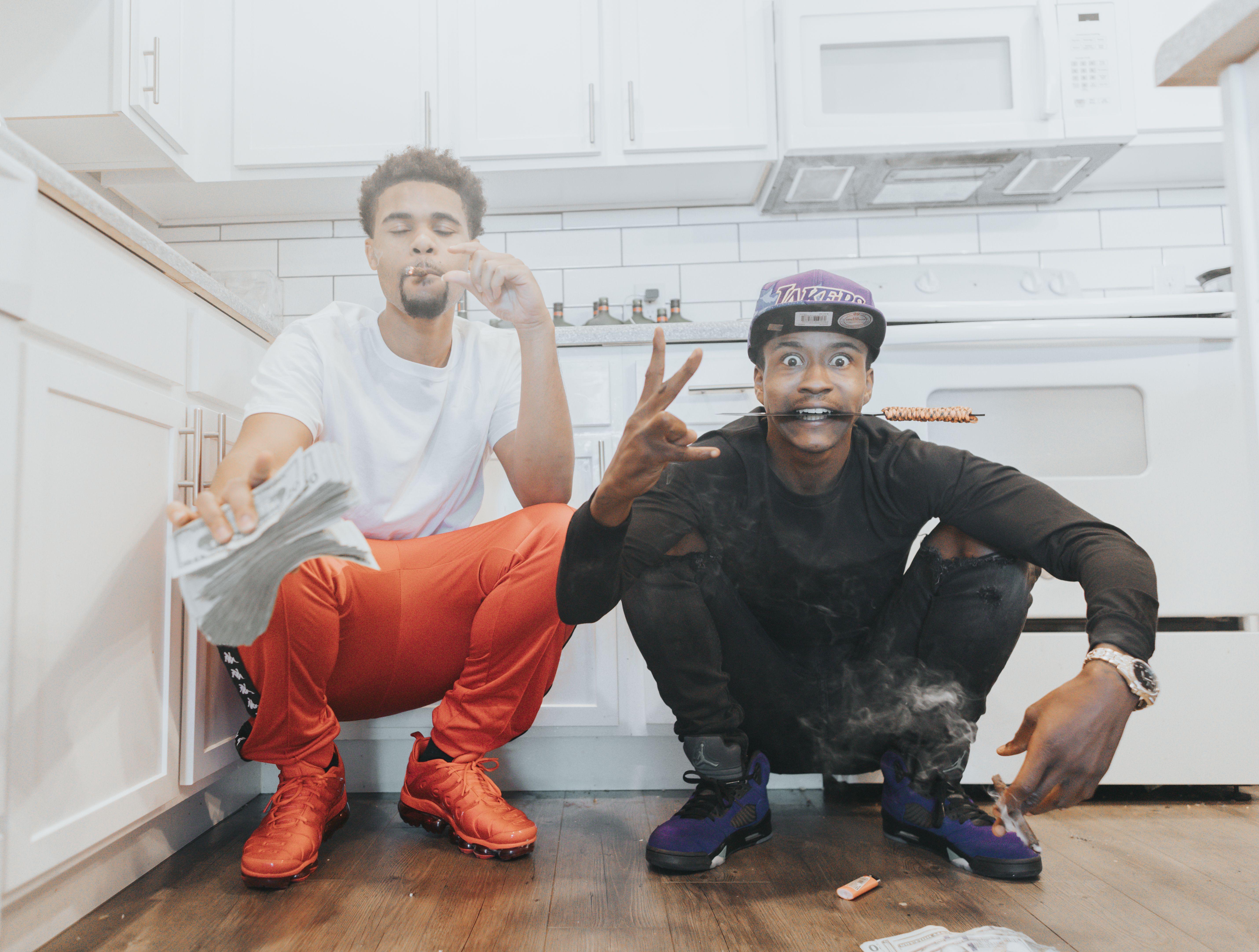 Two young men pose indoors in a relaxed setting, capturing a moment of urban lifestyle.