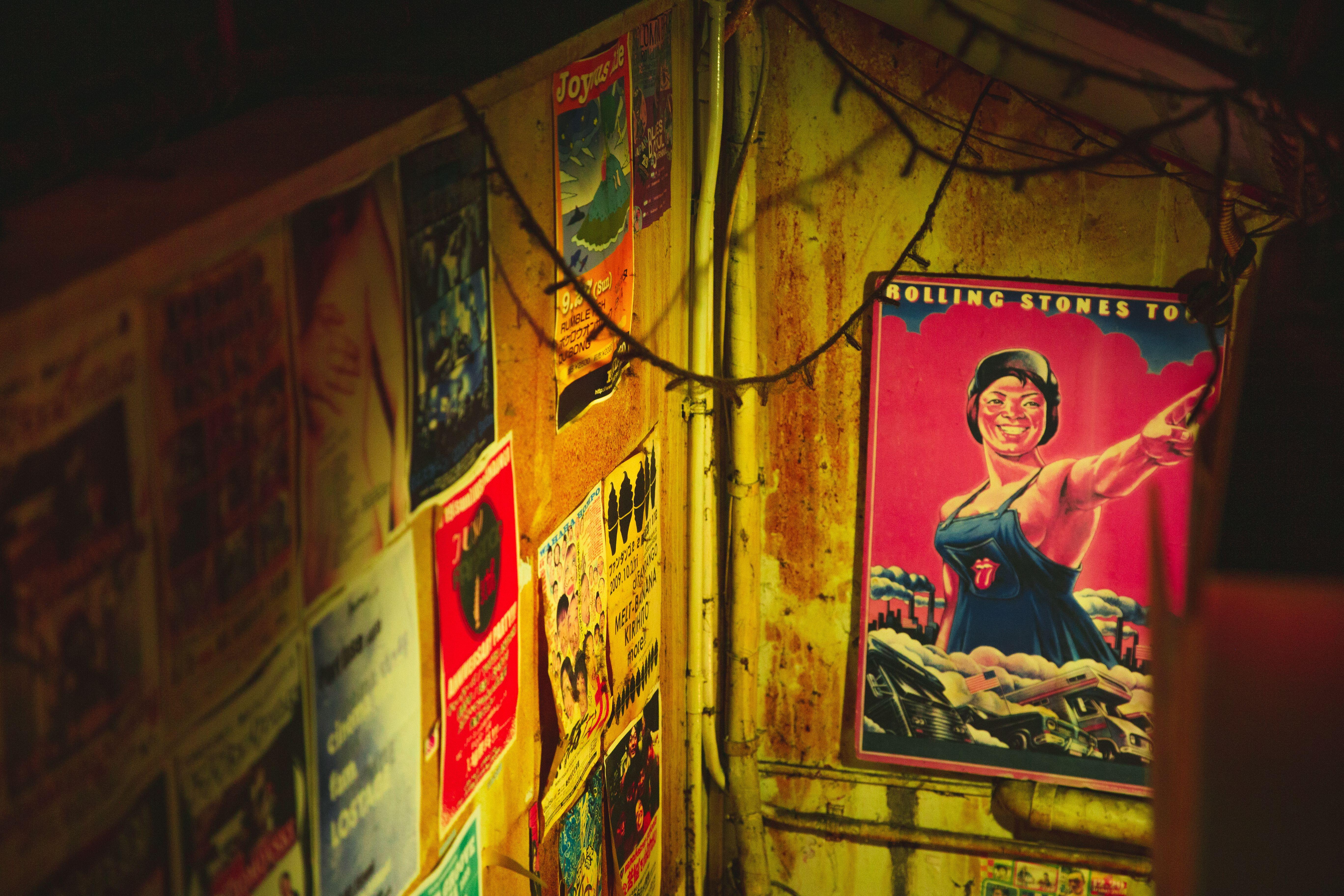 High angle of different placards of musical group on metal walls of weathered construction
