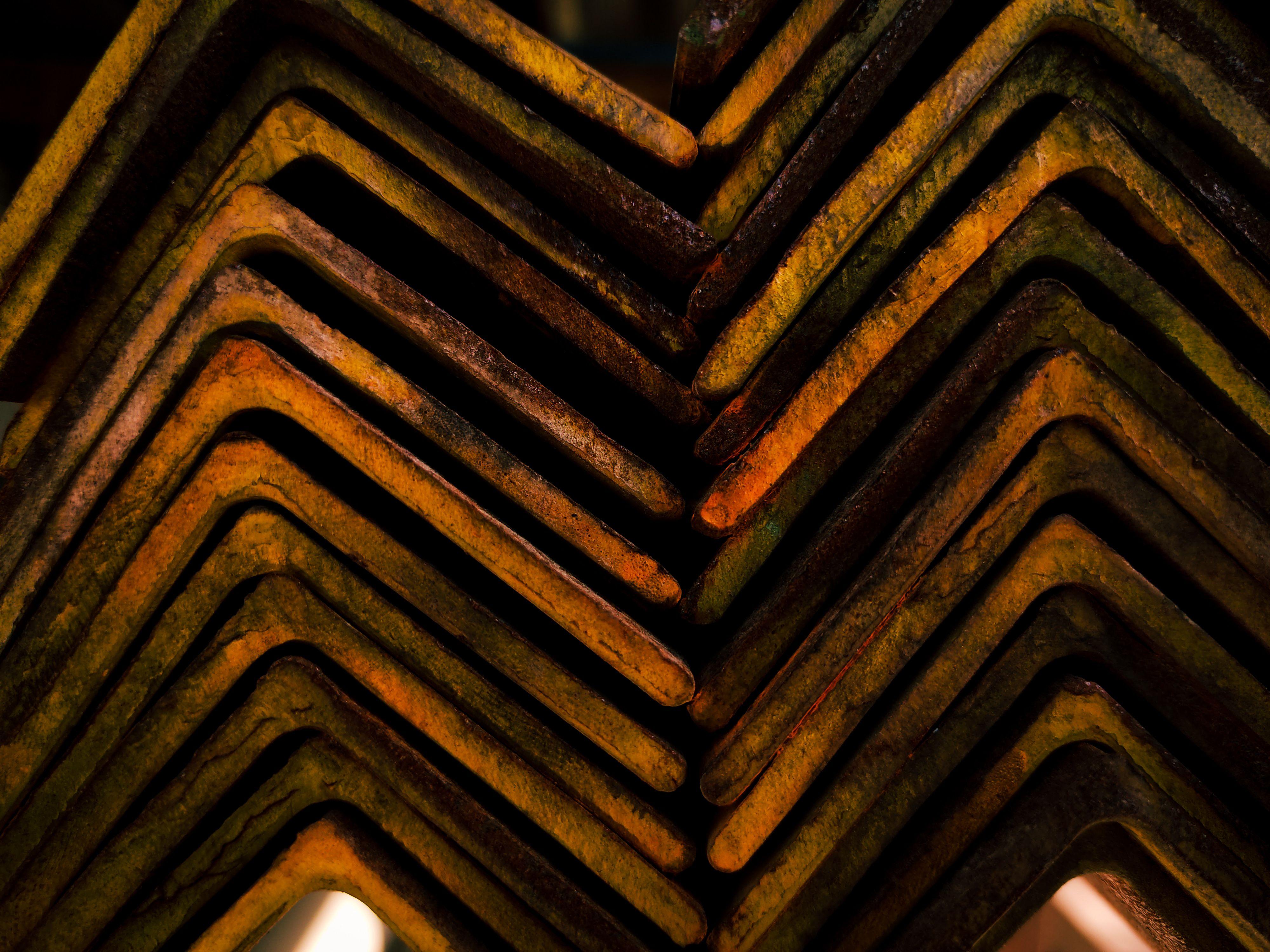 Close-up of rusty steel beams arranged in a geometric pattern, showcasing industrial texture.
