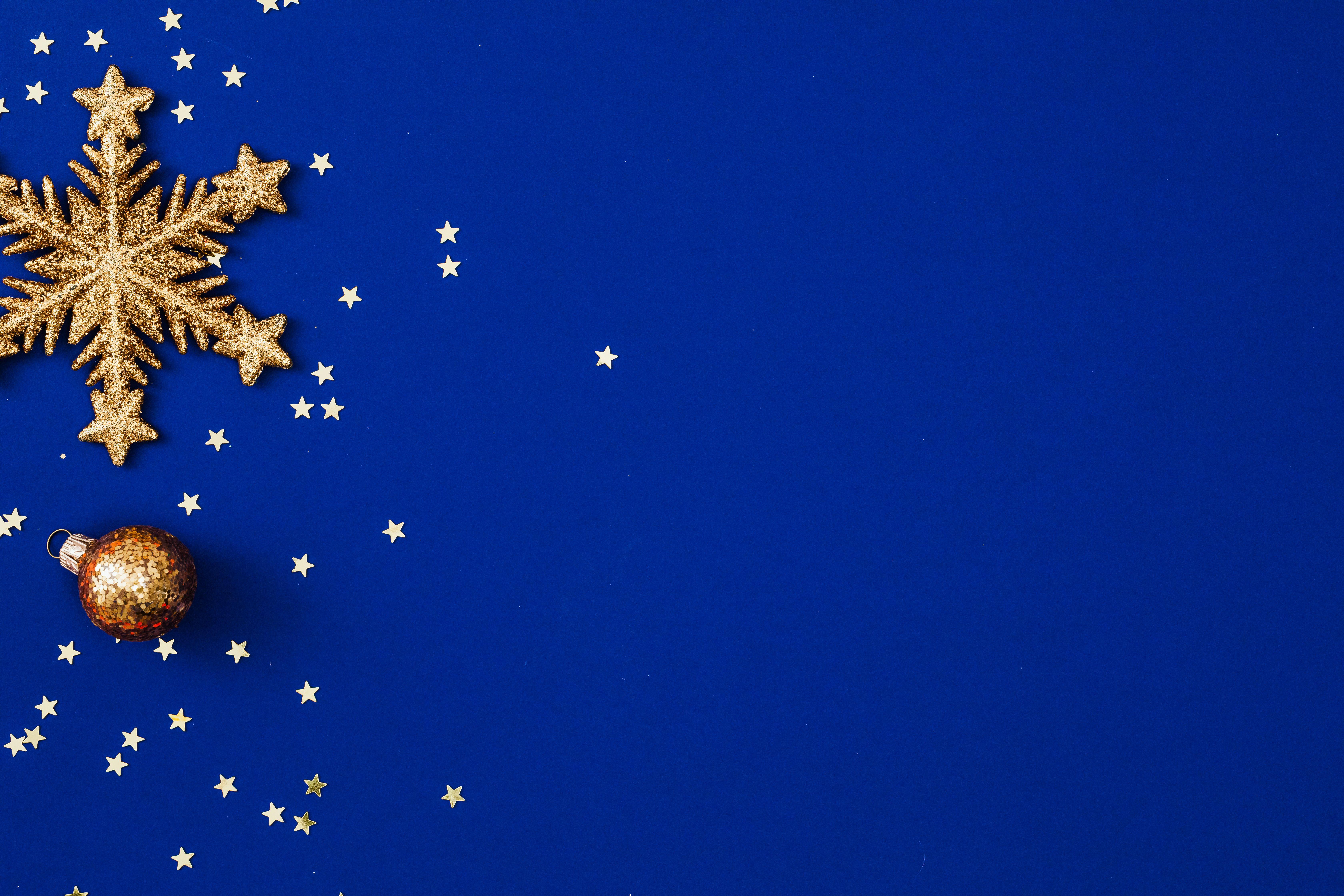 Golden snowflake and bauble with star decorations on blue background.