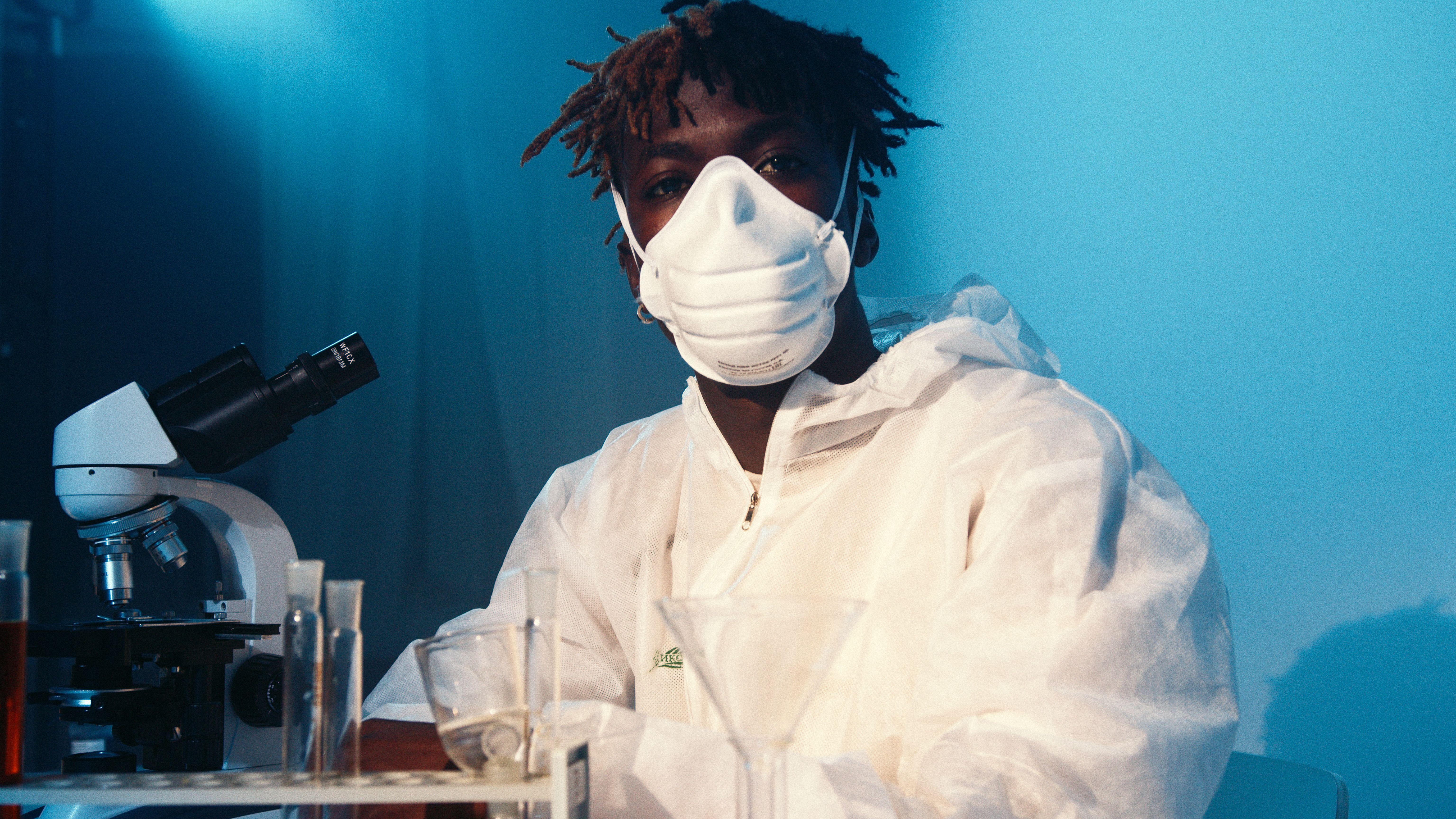 Scientist in protective gear using a microscope for research in a laboratory.