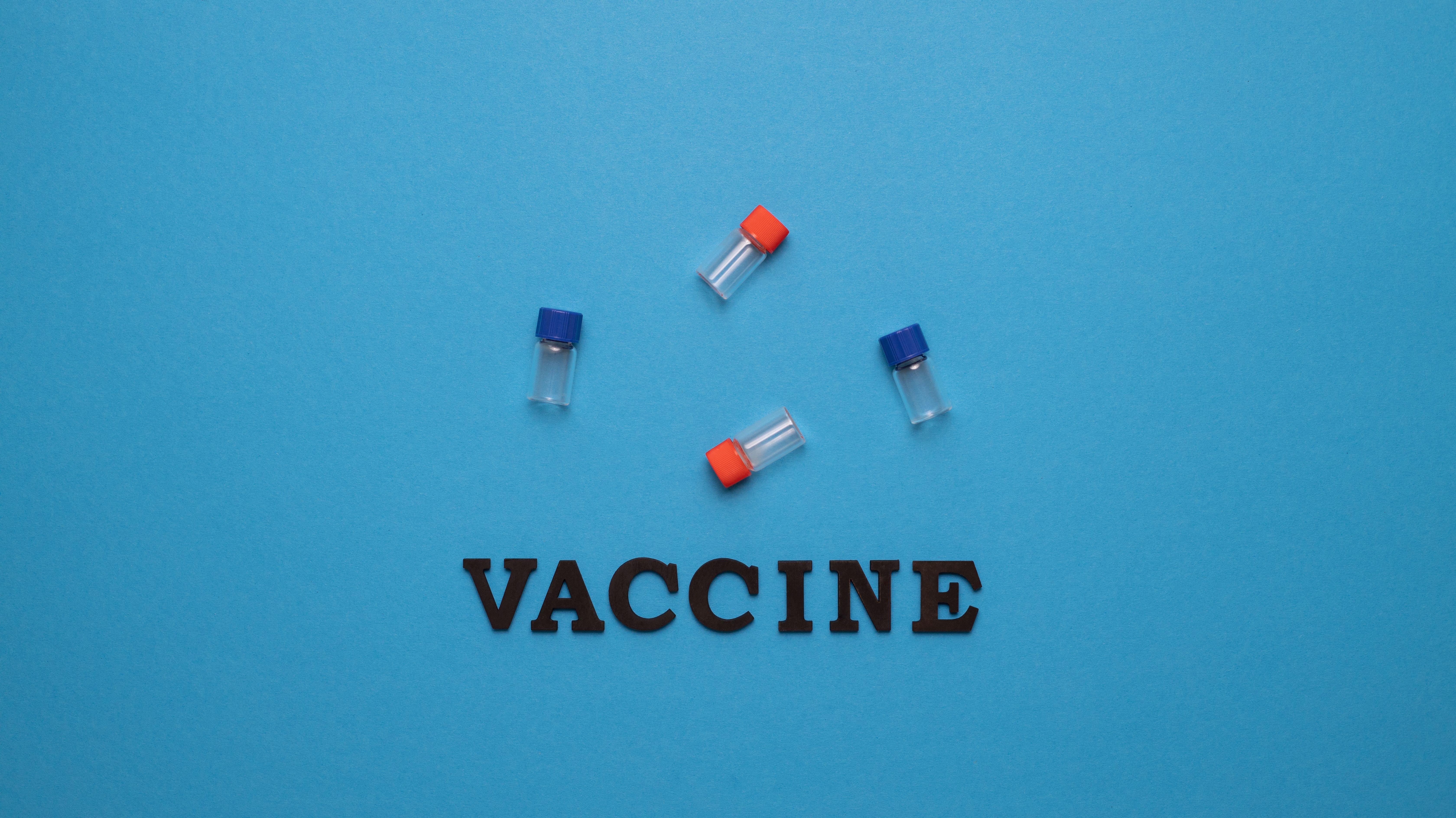 Three small vials and the word 'VACCINE' on a blue background, representing vaccination and health.