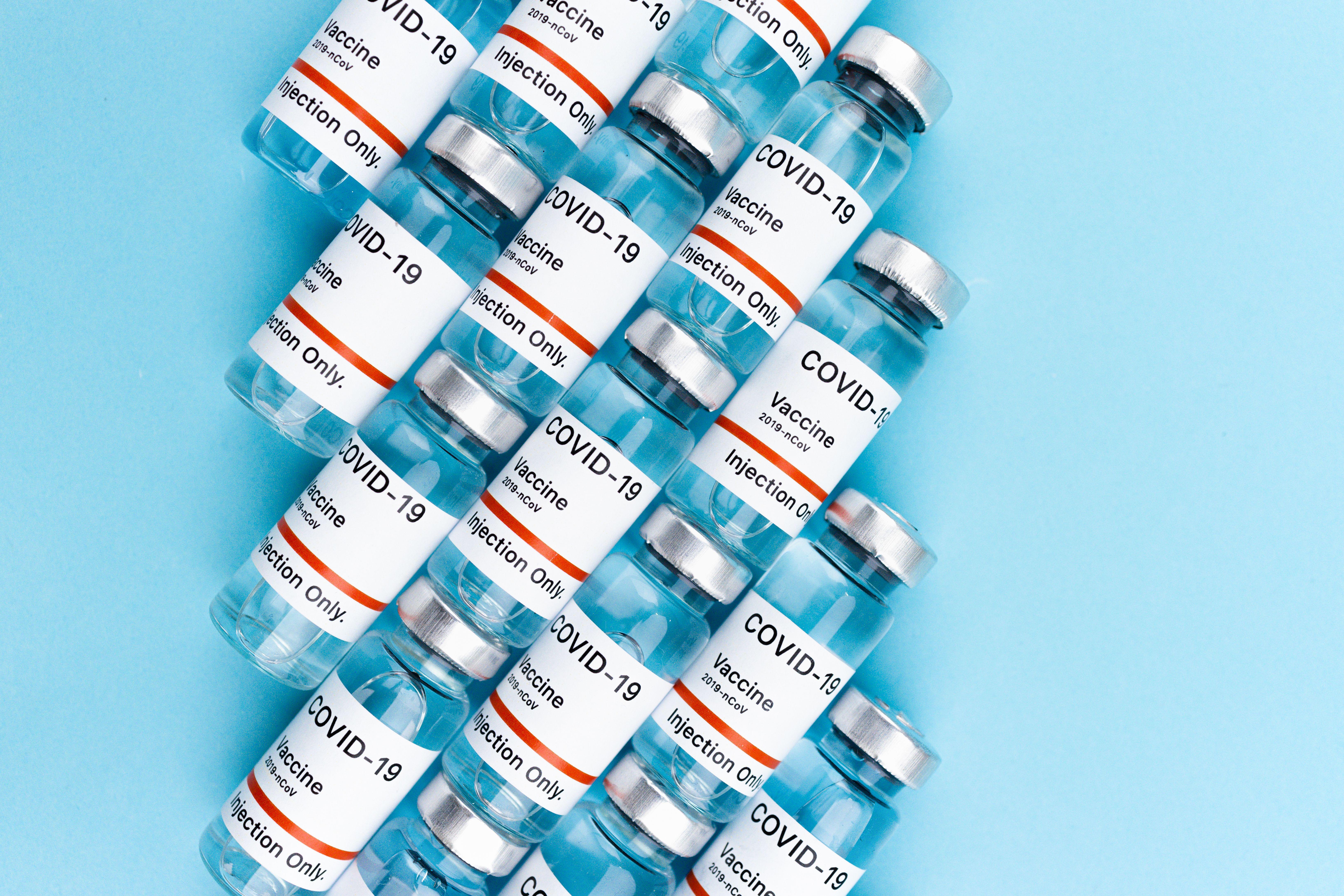 Top view of COVID-19 vaccine vials arranged on a blue surface, highlighting vaccination and pandemic themes.