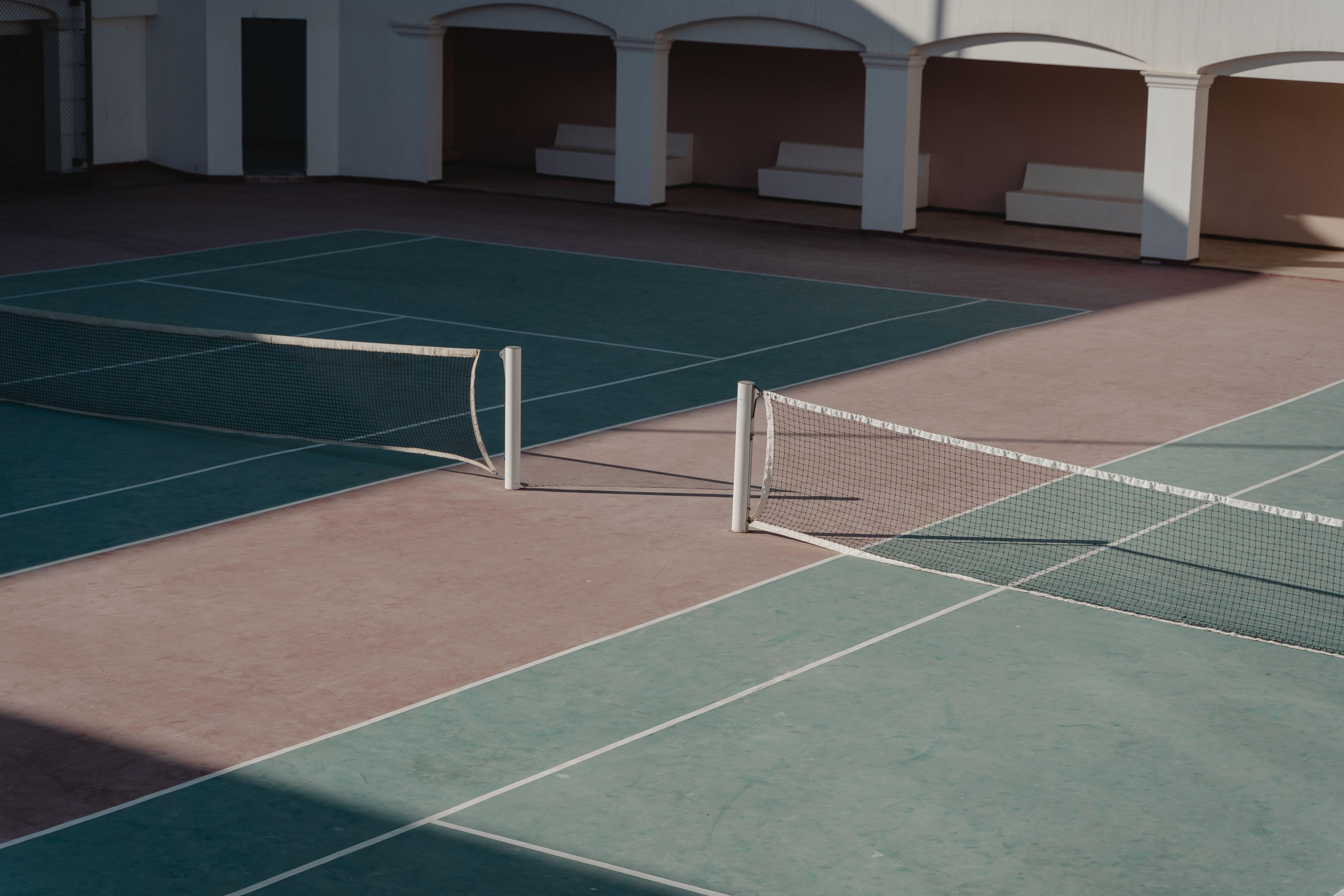 A deserted tennis court with shadows casting over the net, creating a serene atmosphere.