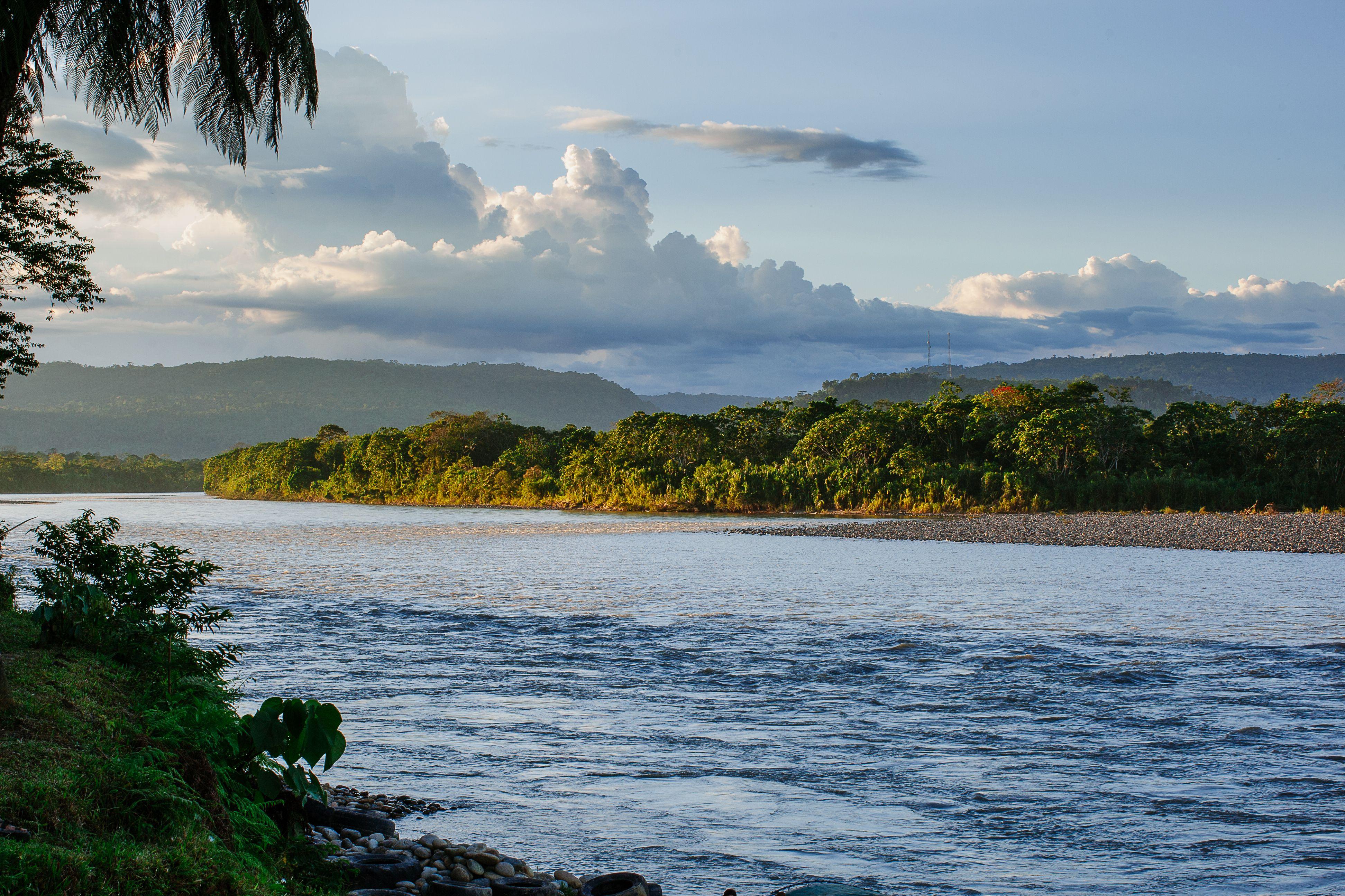 Beautiful landscape of the Tena River with lush green forest and blue sky.