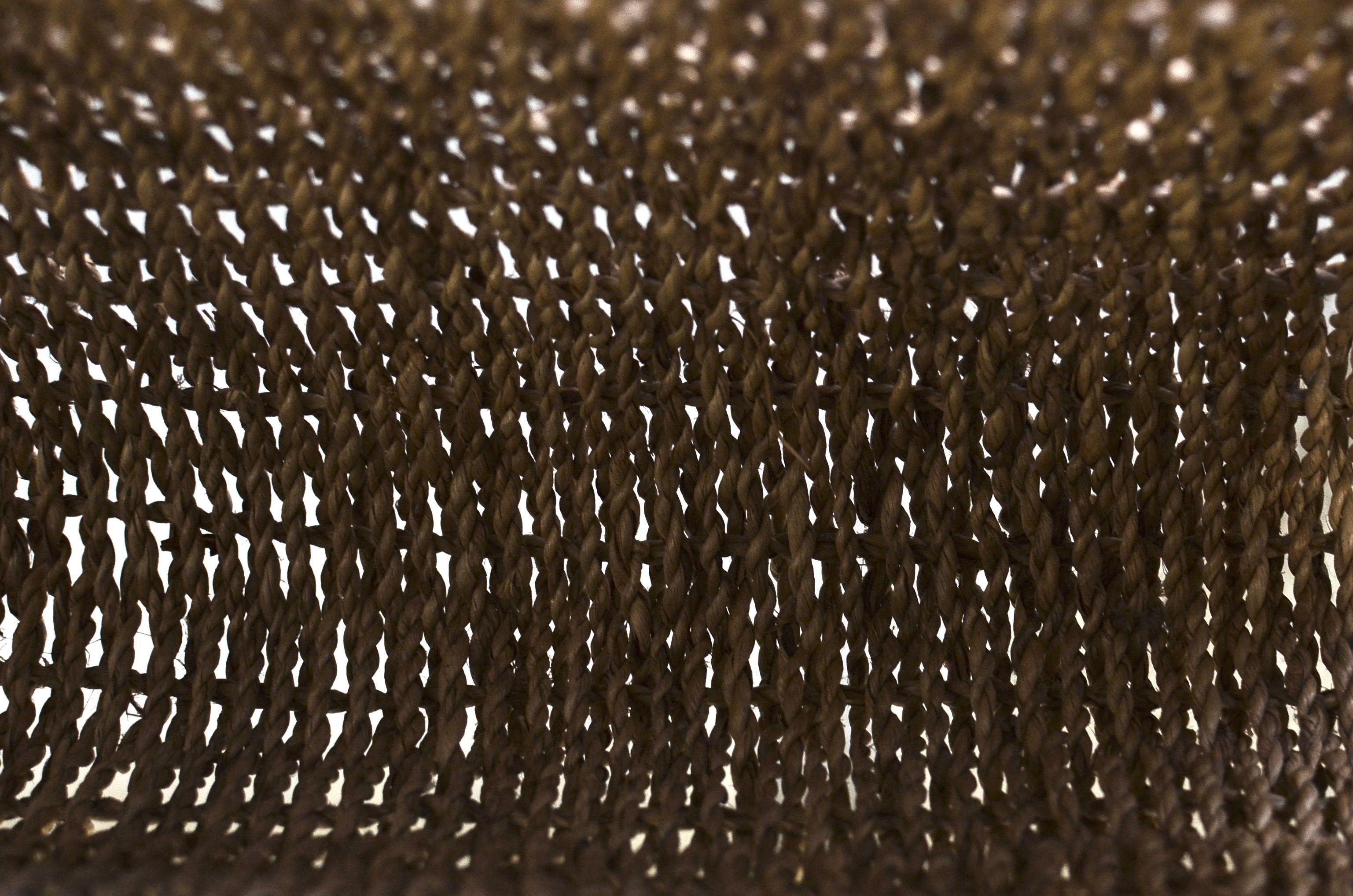 Textured wicker background with dried brown lines creating pattern and sun shining through small holes on street in sunny day