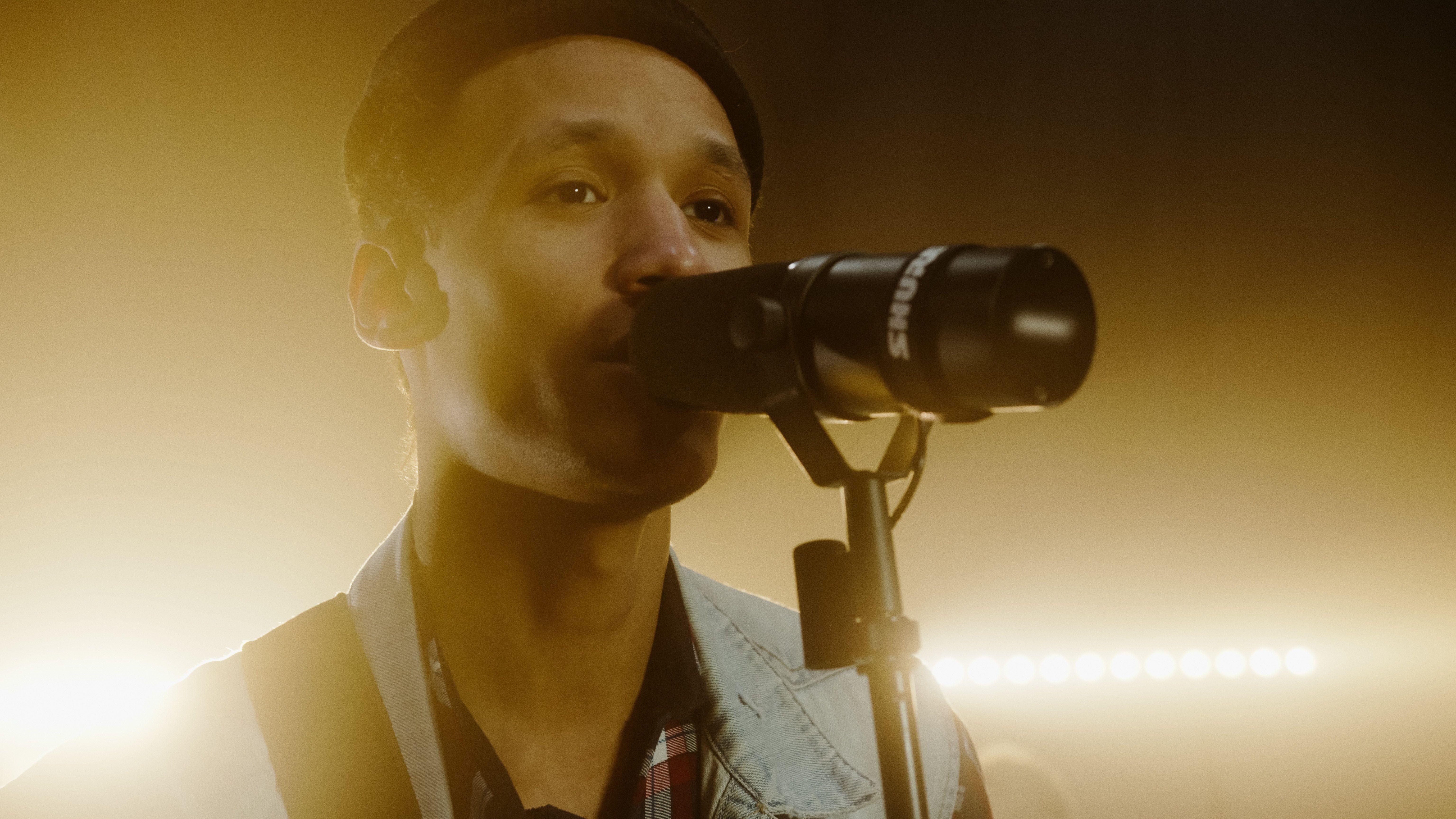 Close-up of a male singer performing passionately with a microphone on stage lighting.