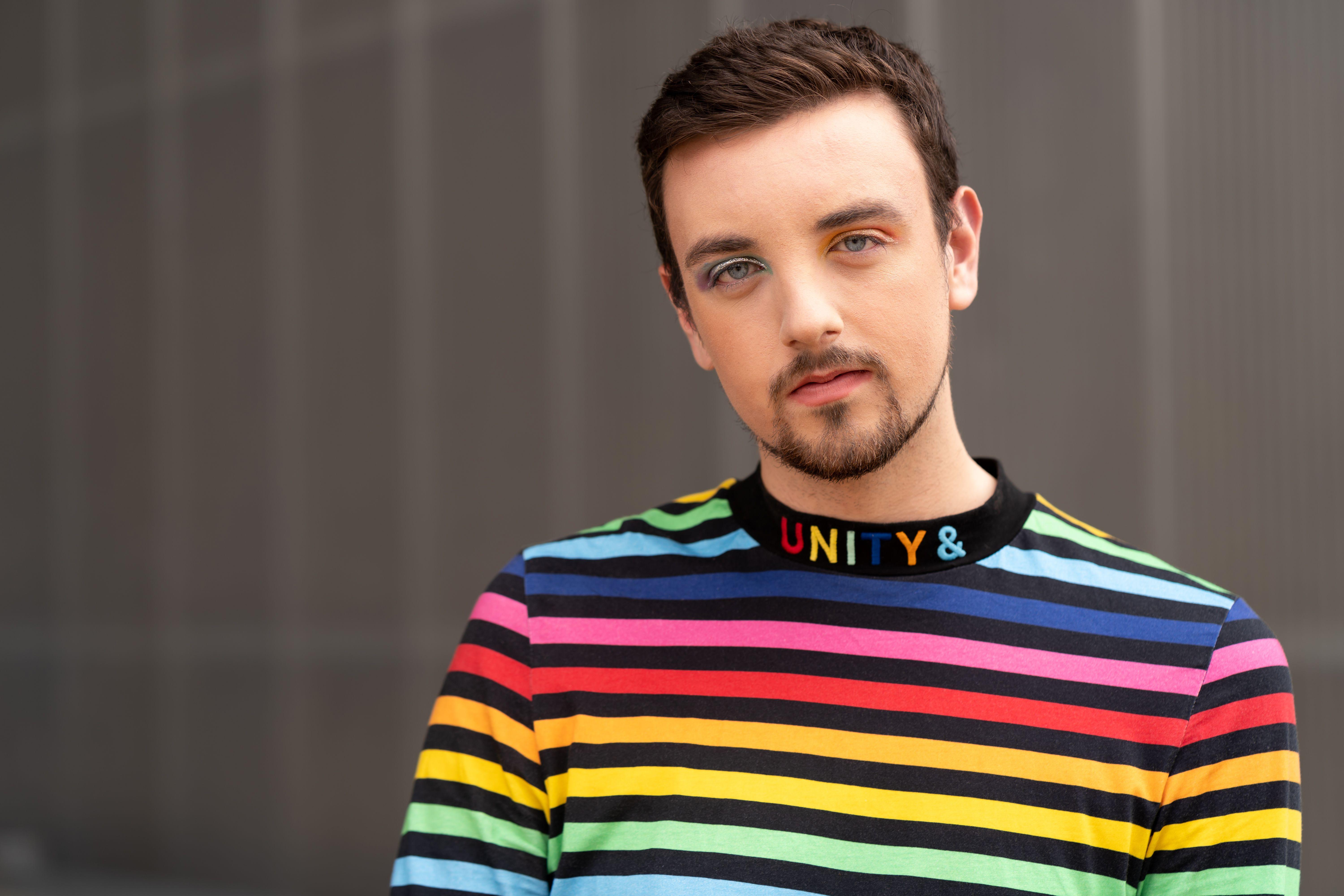 A colorful portrait of a person wearing a rainbow-striped top, symbolizing unity and diversity.