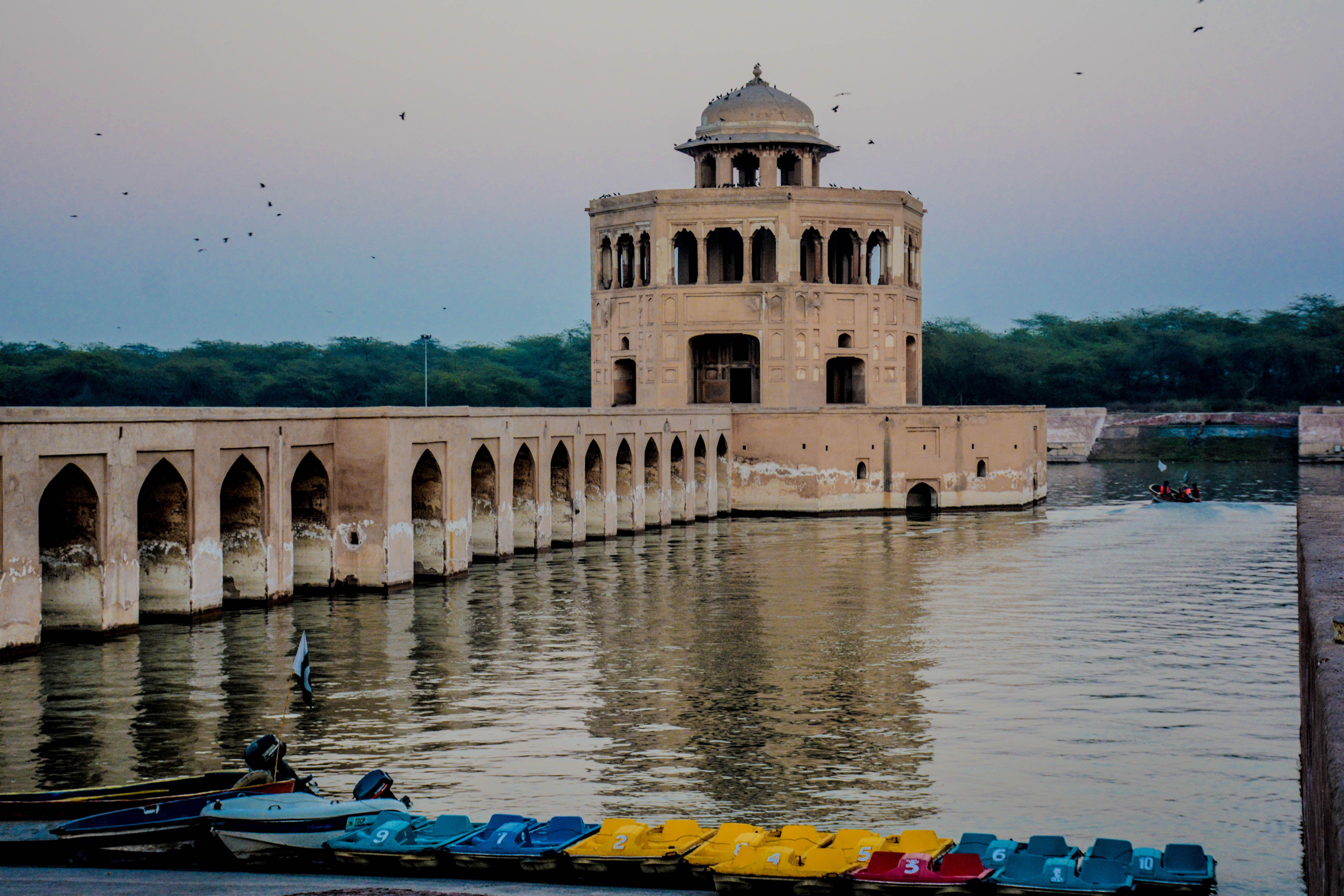 Serene view of Hiran Minar pavilion with boats at sunset in Sheikhupura, Pakistan.